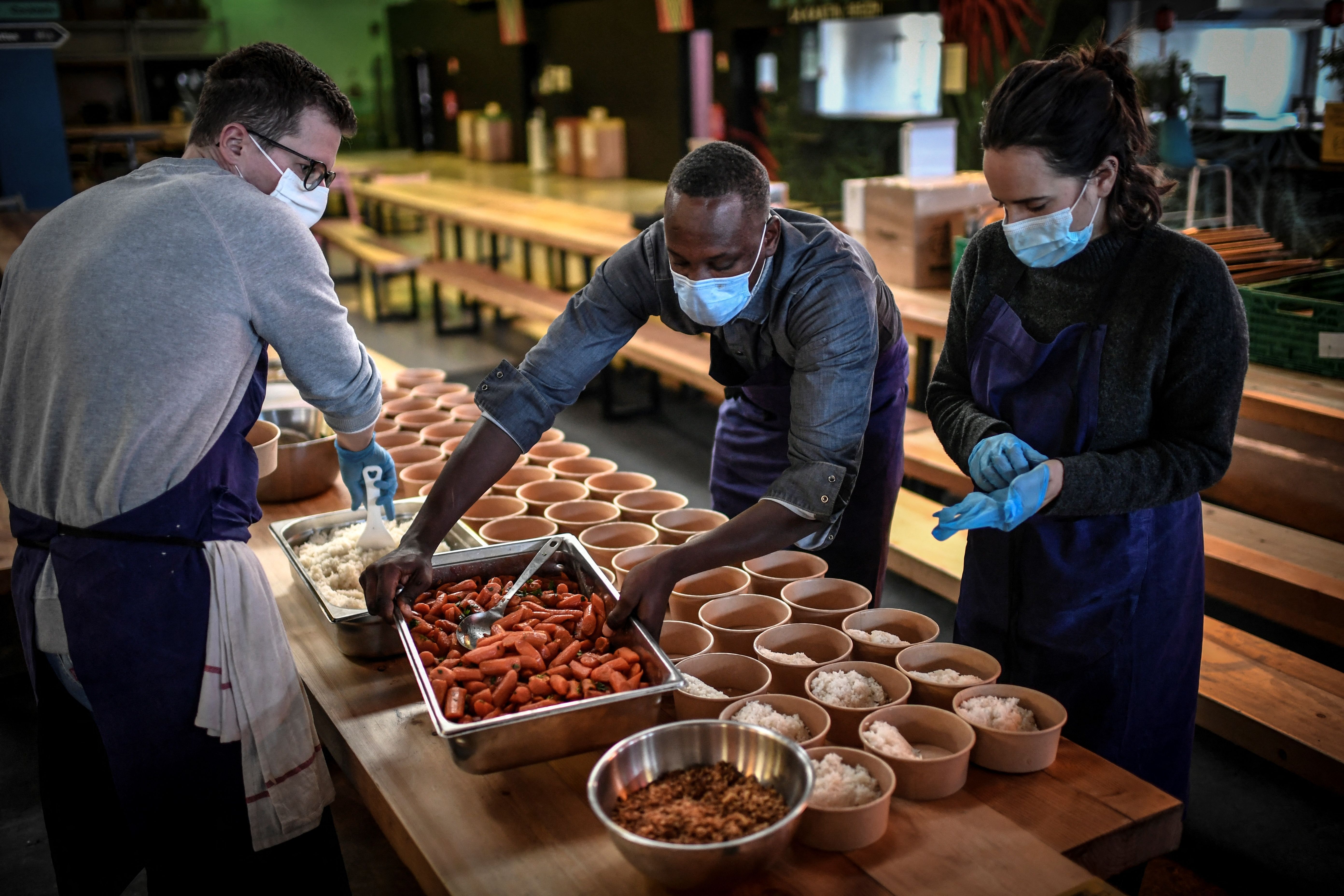Volunteers prepare food for students in need prior to a food distribution to help the most vulnerable people on March 9, 2021 in Paris.