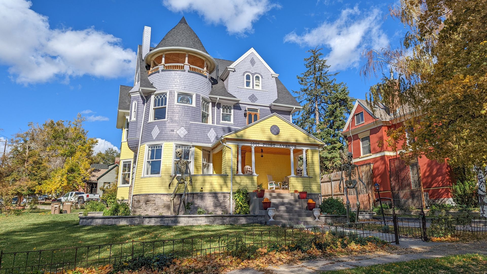 An large blue and yellow Queen Anne house with a turret