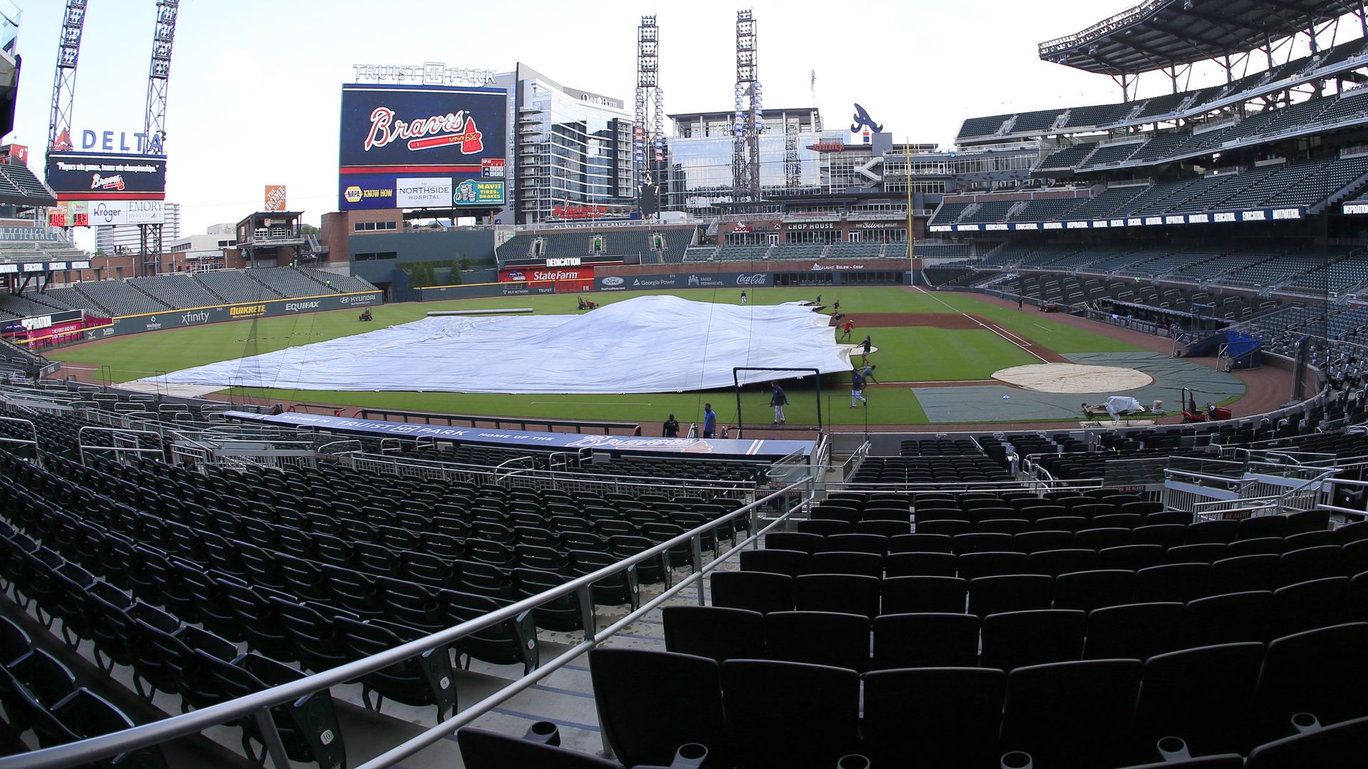 The grounds crew pulls the tarp over the field as a brief summer shower passes overhead before an intrasquad game during the Atlanta Braves Summer Camp, on July 19, 2020, at Truist Park, Atlanta, GA.