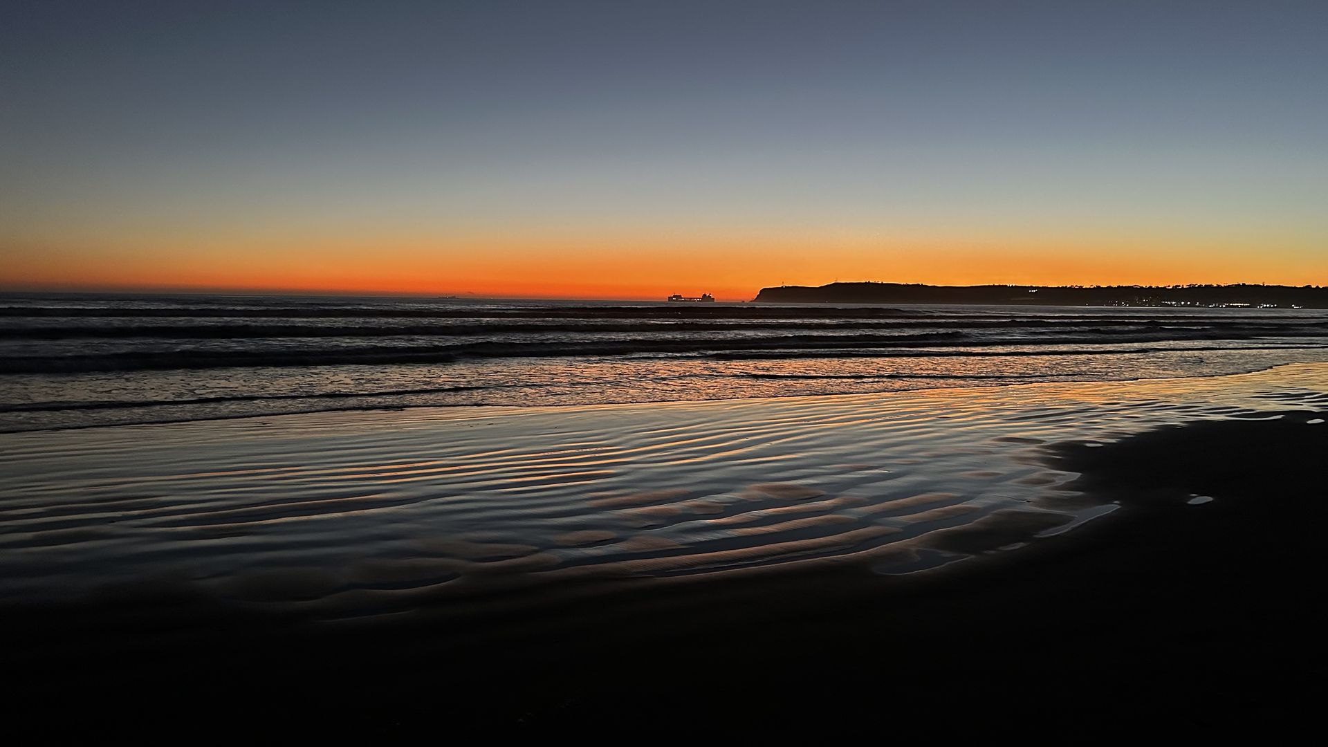 A sunset over the Pacific Ocean with a cliff jutting out