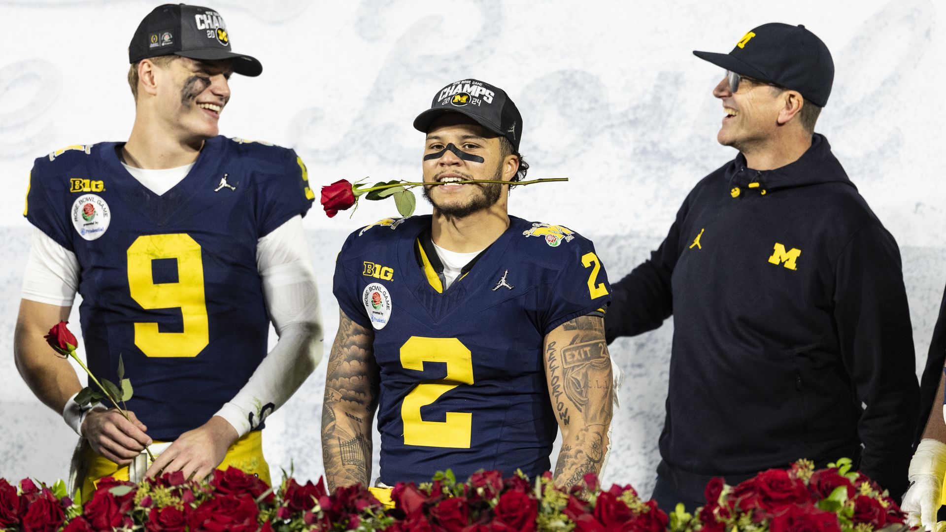 J.J.McCarthy #9, Blake Corum #2 and Head Coach Jim Harbaugh of the Michigan Wolverines celebrate their Rose Bowl victory between University of Alabama and University of Michigan at the Rose Bowl. Corum has a rose in his mouth on stage.