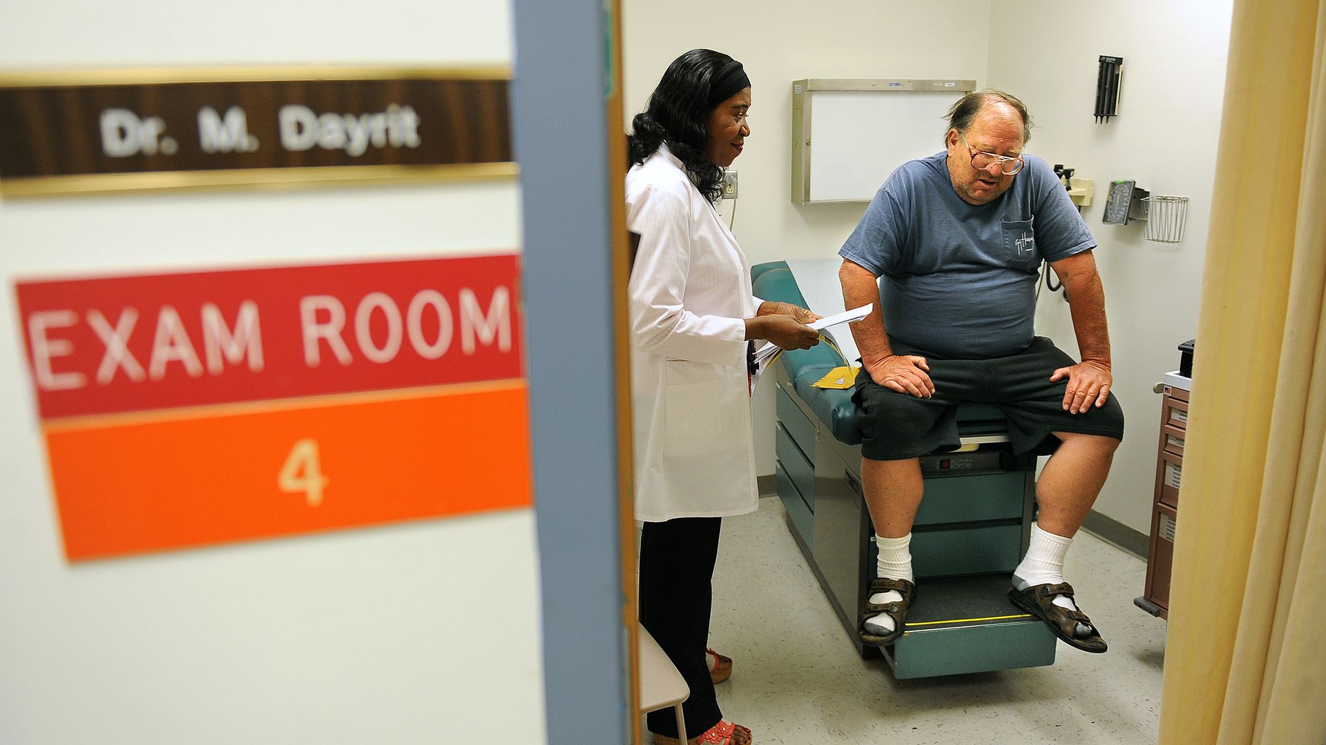 A doctor visits with a patient in an exam room