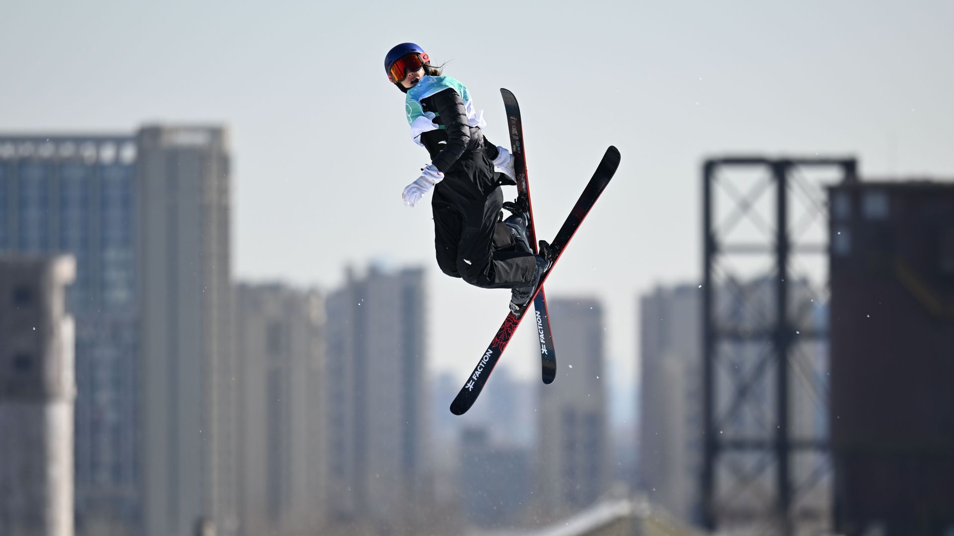 Eileen Gu jumps with Beijing highrises in the background
