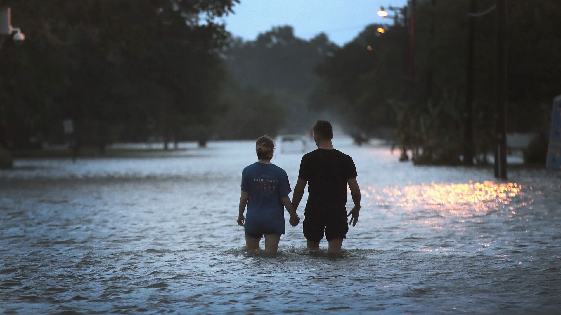 A couple strolls down Lakeshore Drive along the shore of Lake Pontchartrain after it was flooded in the wake of Hurricane Barry on July 13, 2019 in Mandeville, Louisiana.