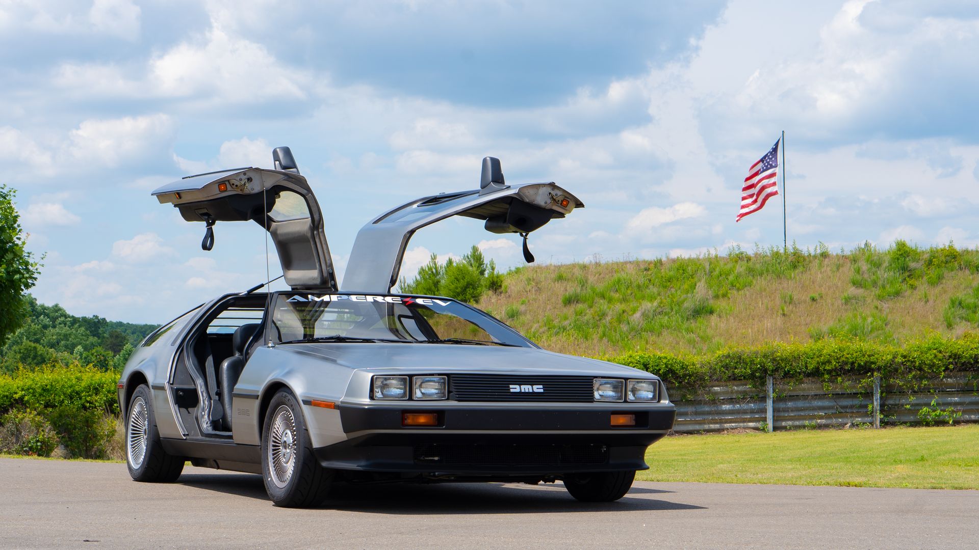 DeLorean with its doors up and an Ampere EV decal on the windshield 