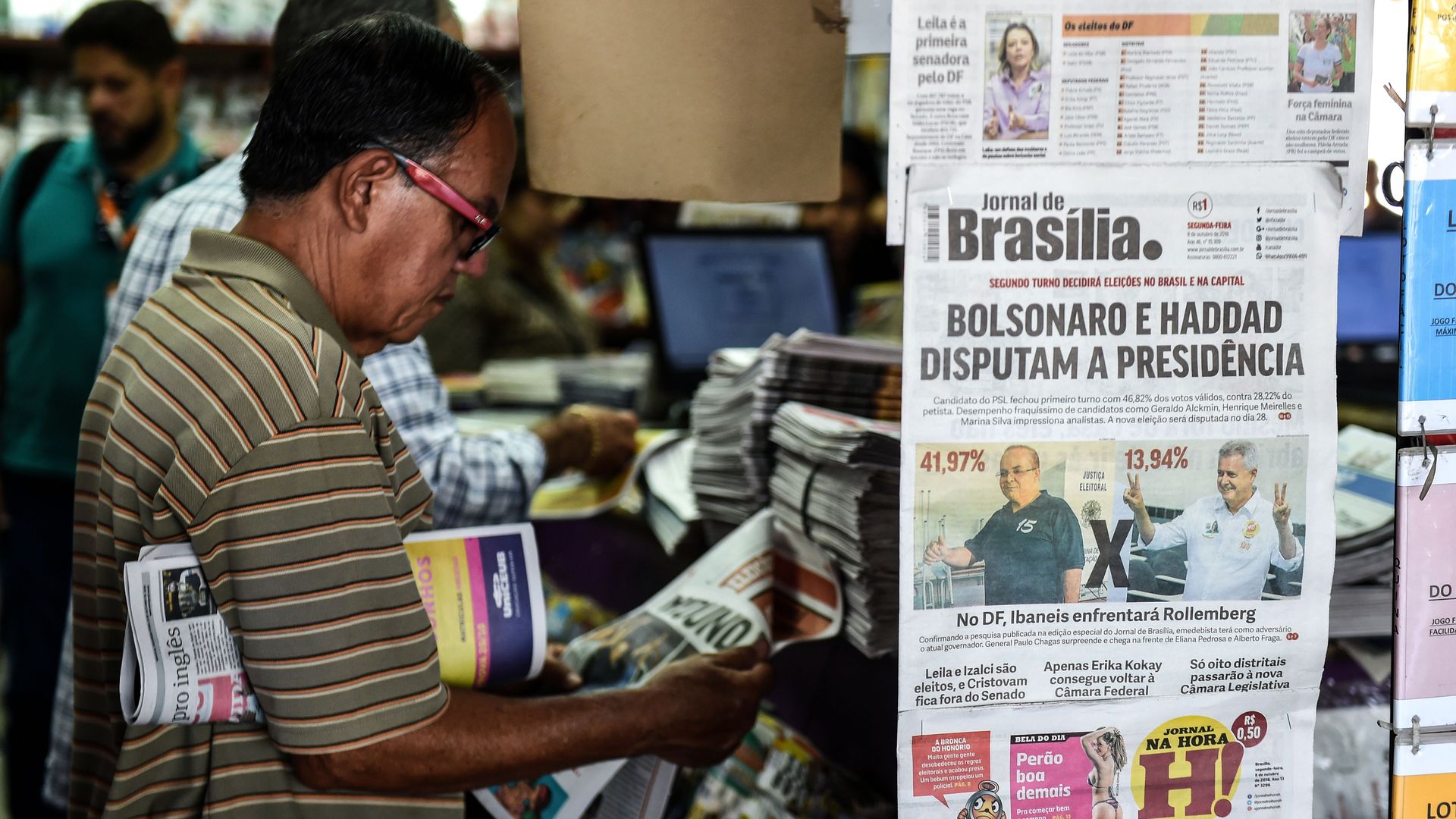 mans looking at newspapers at Brazilian newsstand