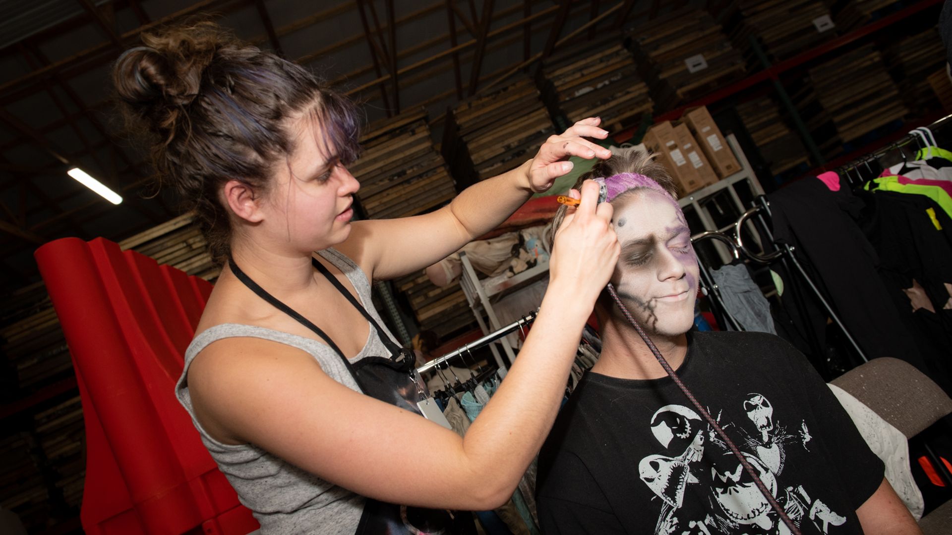 Cianna Gaston applies airbrush zombie makeup to a person's face