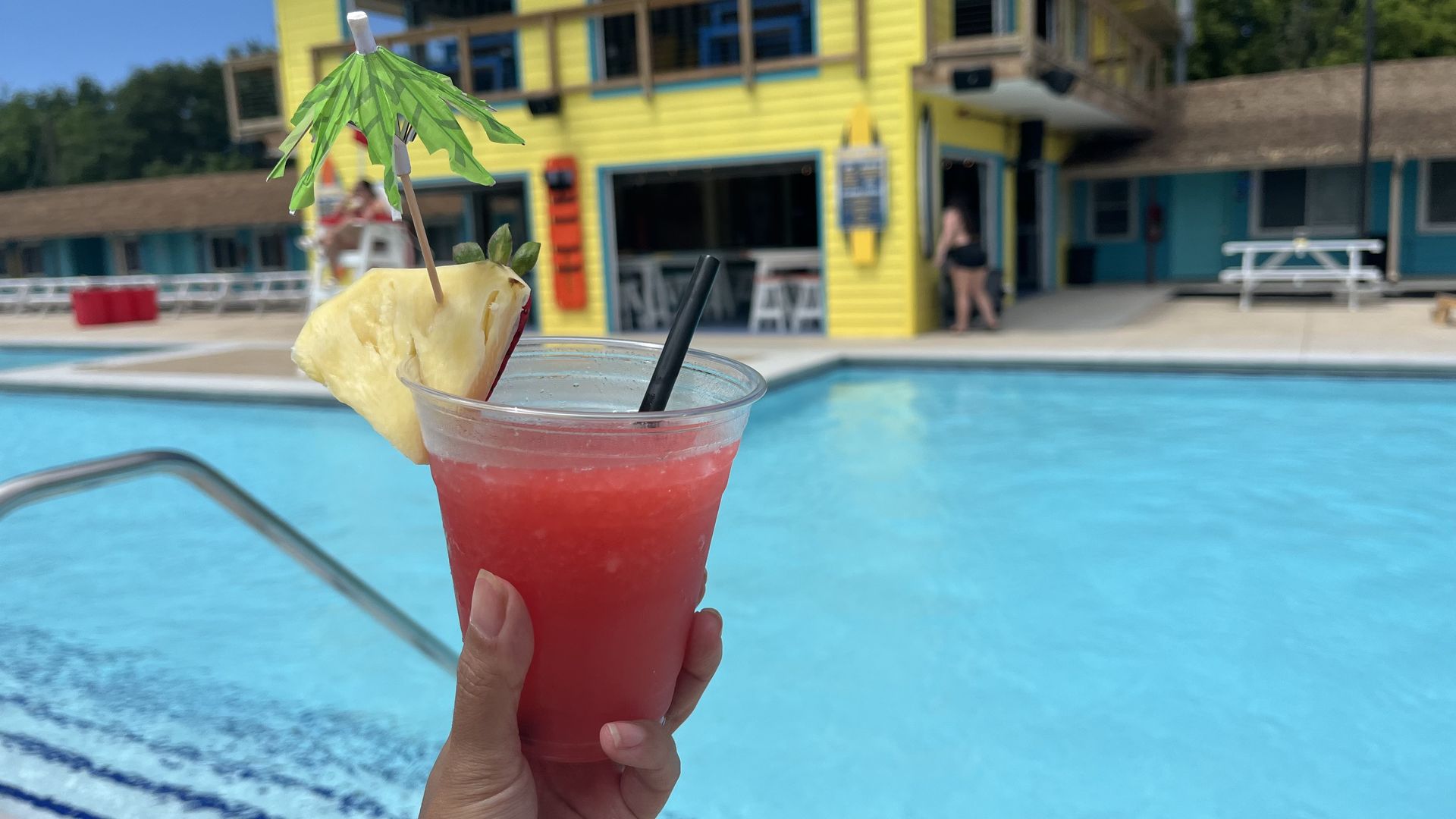 A held up drink in front of a pool