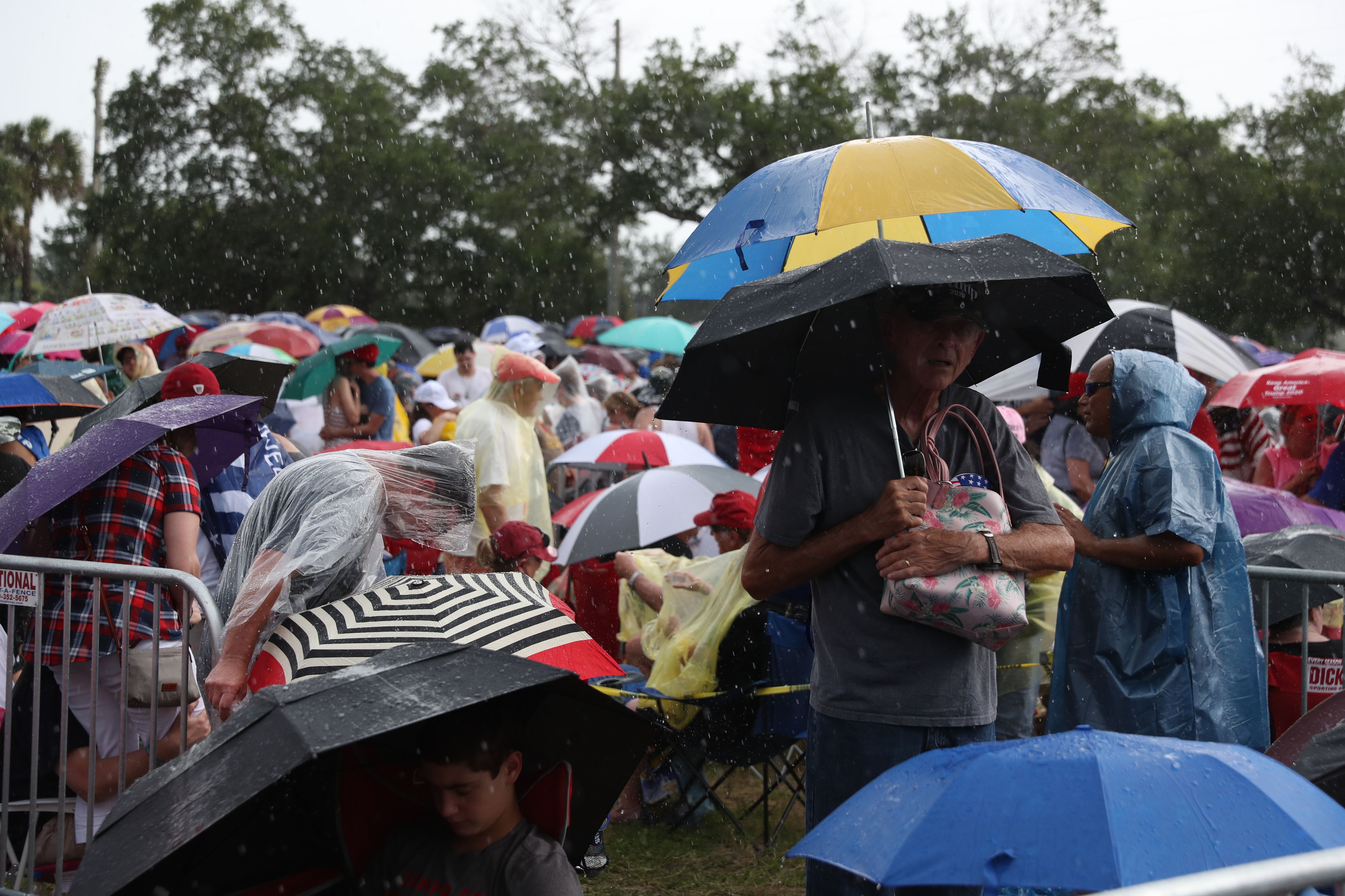Hordes of people standing under umbrellas to avoid the rain. 