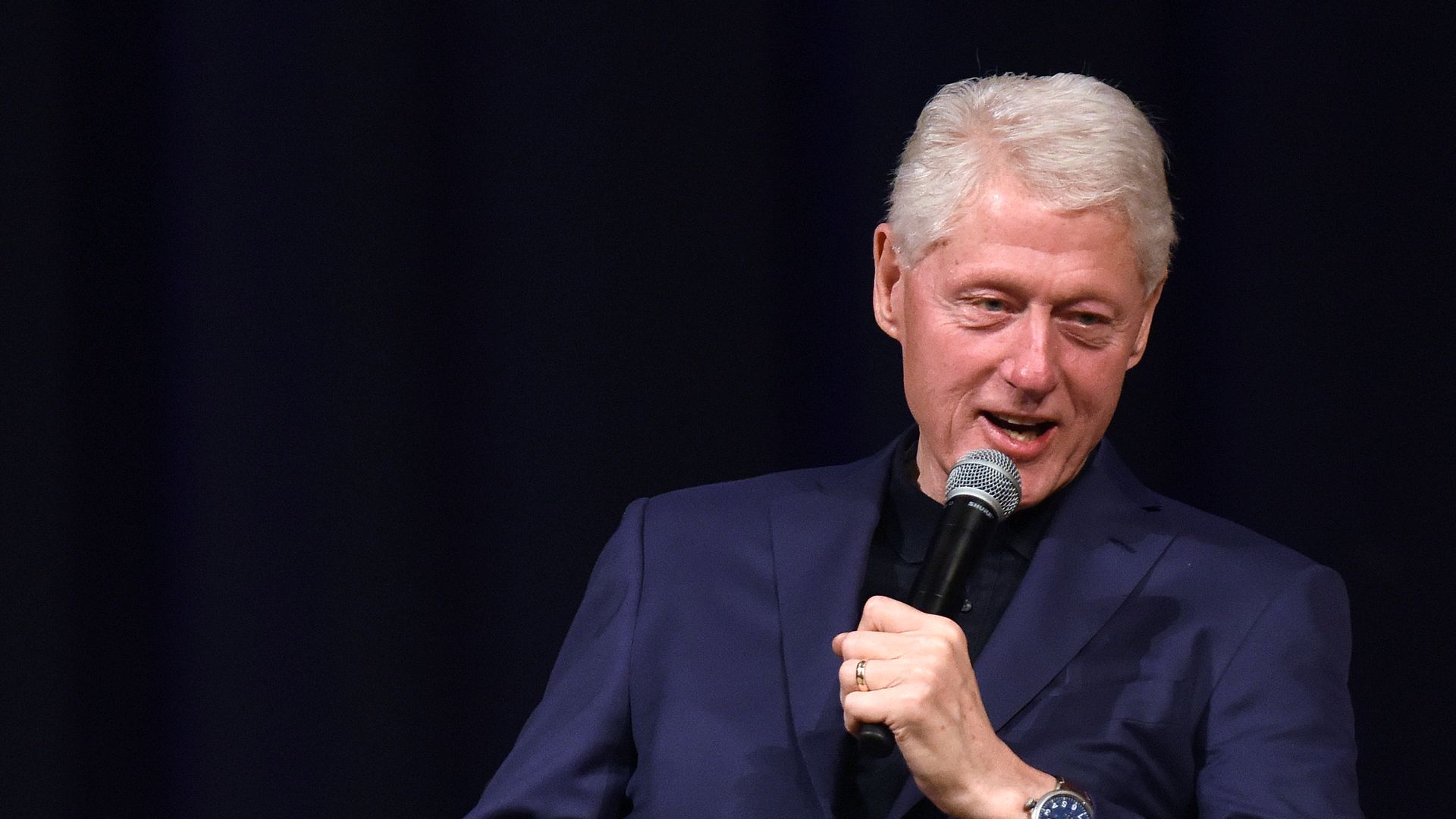 Bill Clinton speaks with a microphone.