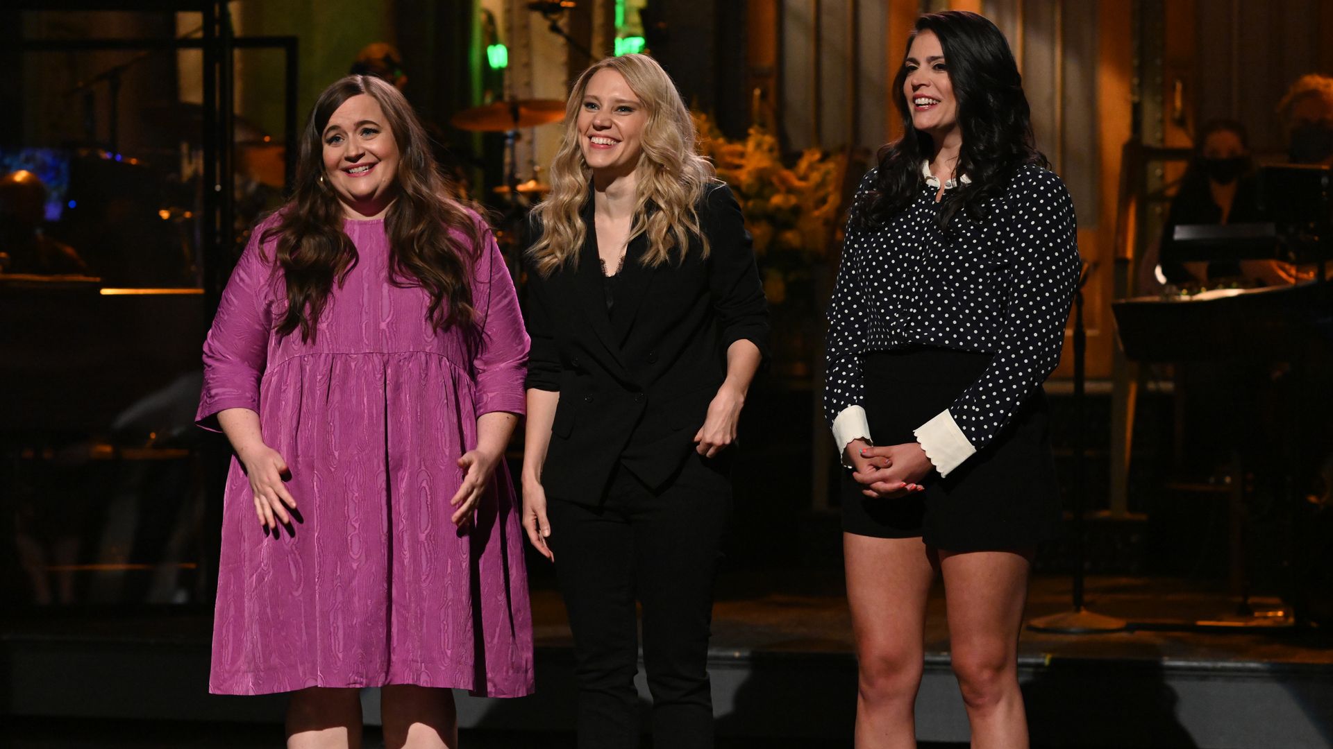 Aidy Bryant, Kate McKinnon and Cecily Strong stand on stage at SNL. 