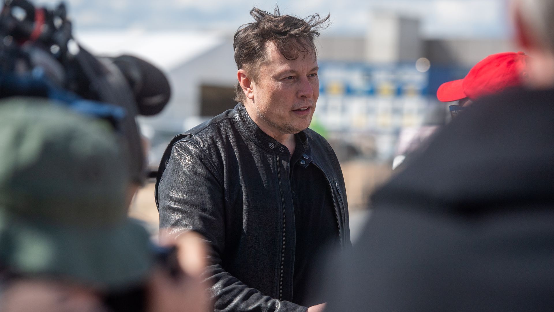 Photo of Elon Musk in black shaking hands with someone outdoors