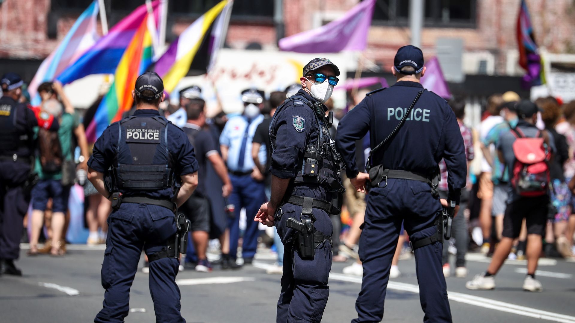 Police standing in front of LGBTQ flags.