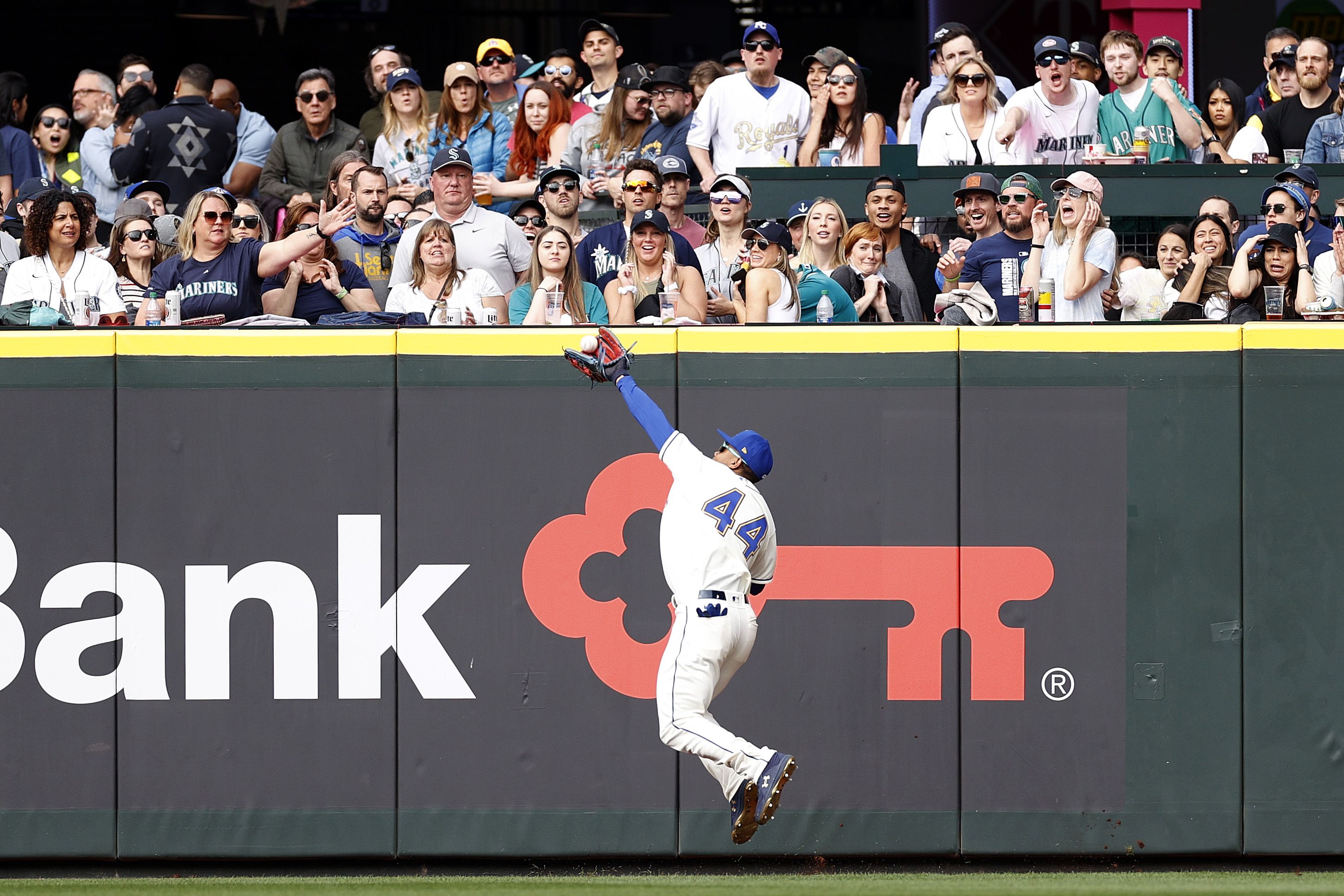 A Seattle Mariners player makes a catch in front of a crowd of fans