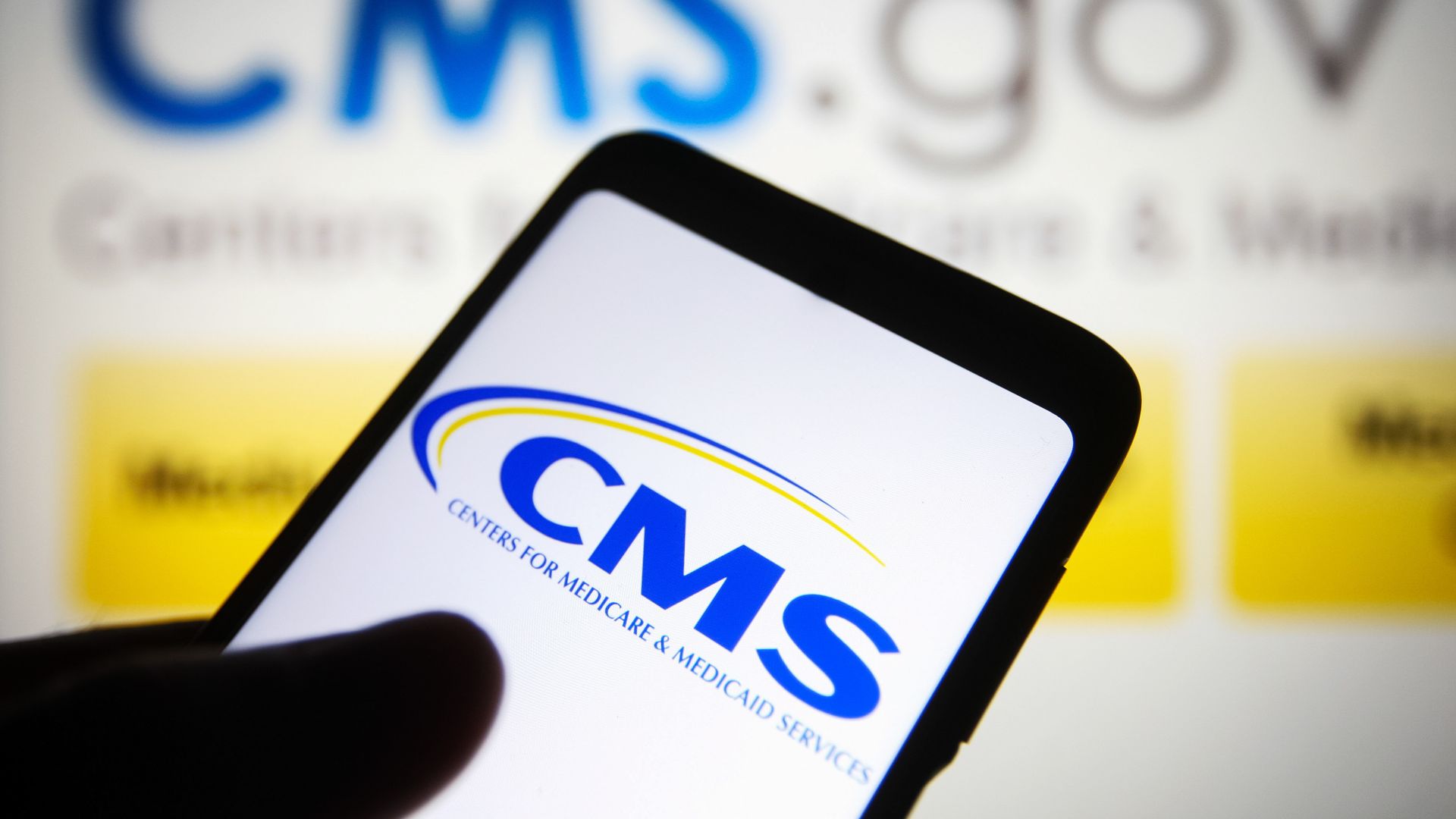 Centers for Medicare & Medicaid Services (CMS) logo is seen displayed on a smartphone and on the background of its website