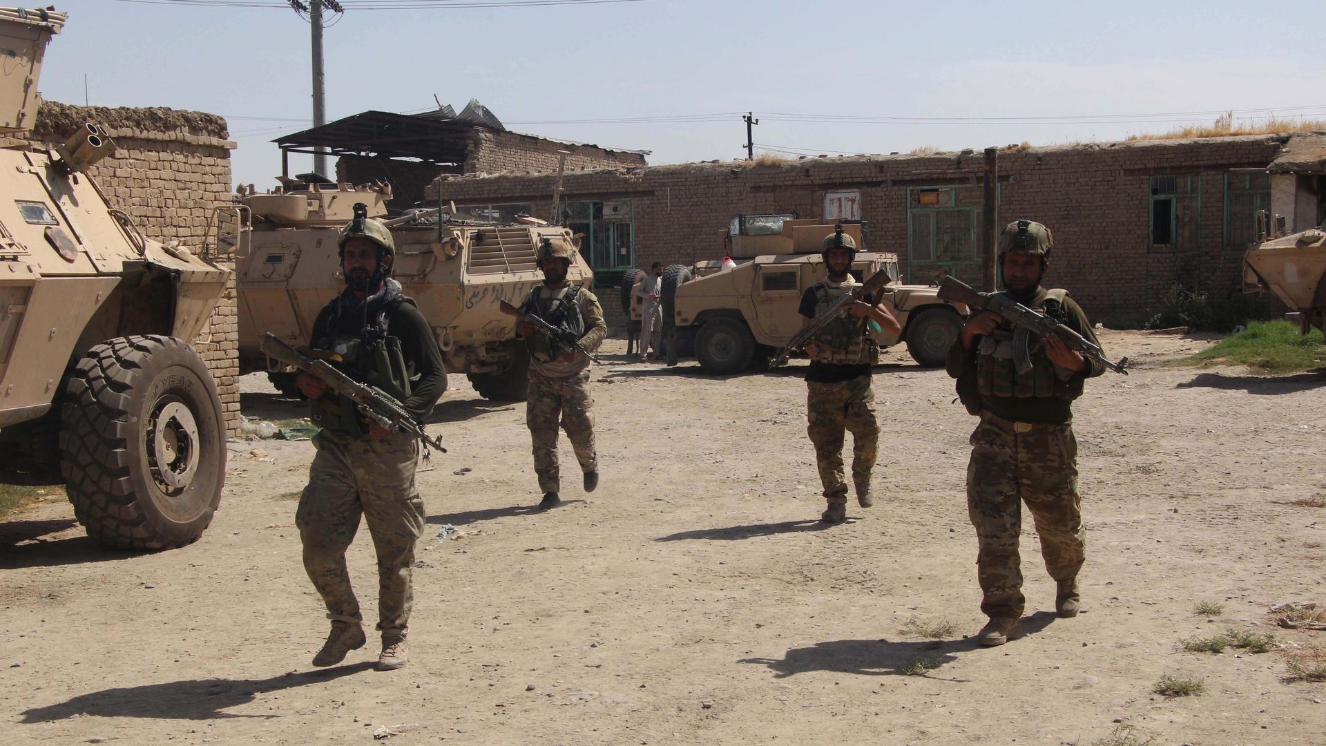 Afghan soldiers in a village, holding rifles and dressed in military gear