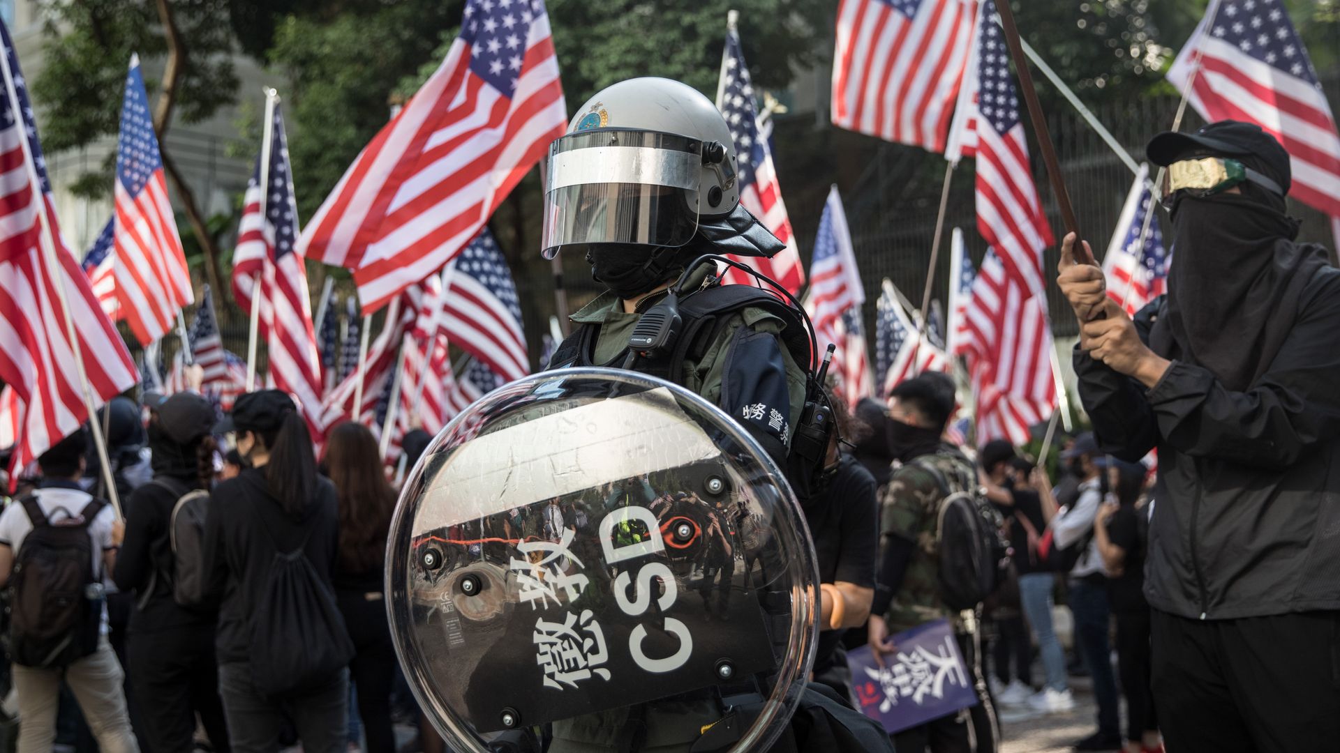 A police officer stands guard as pro-democracy protesters march