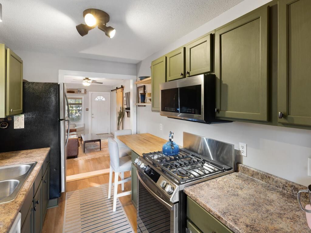 A kitchen with green cabinets and marble countertops.