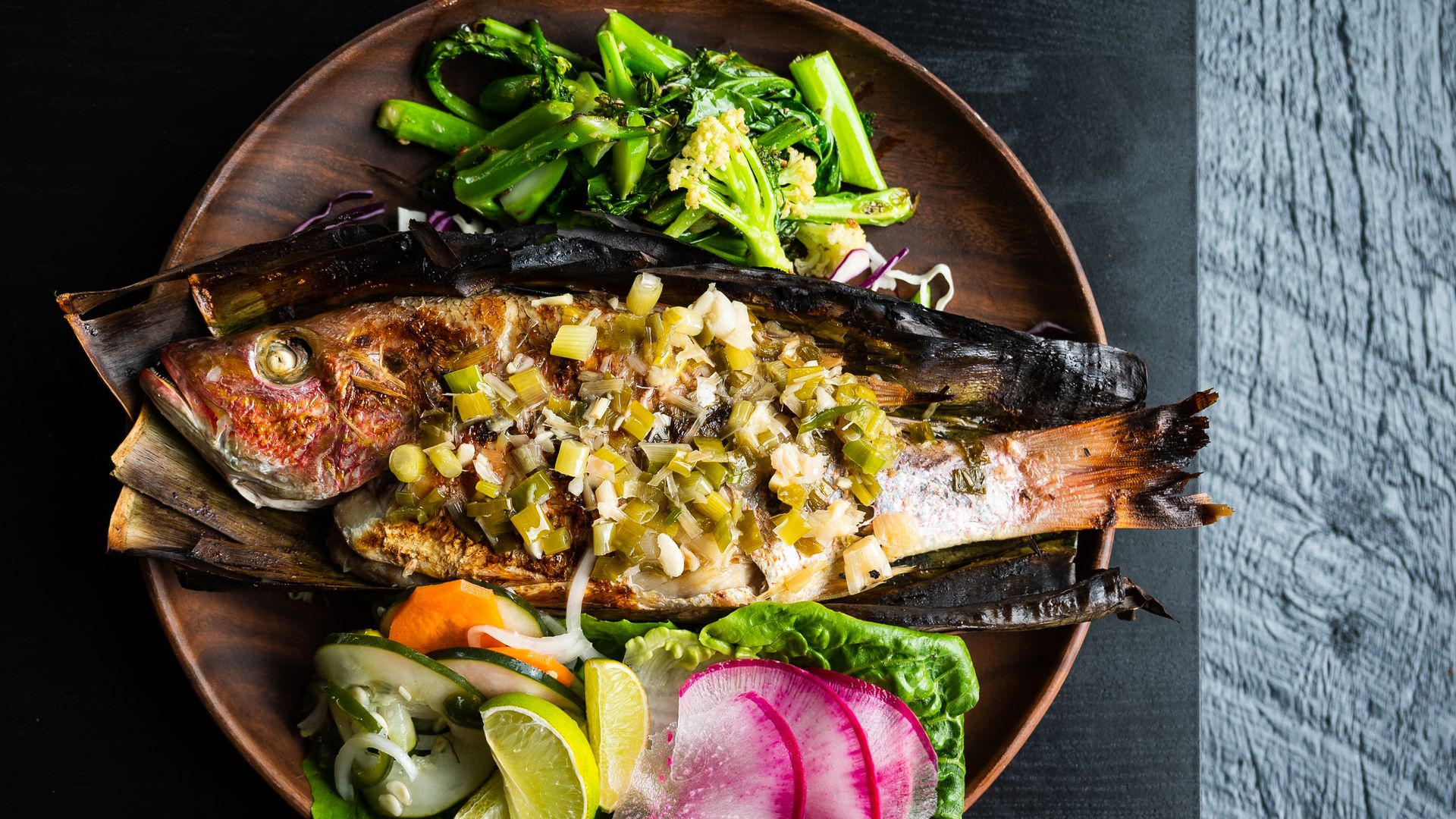 A photo of a whole fish and vegetables.