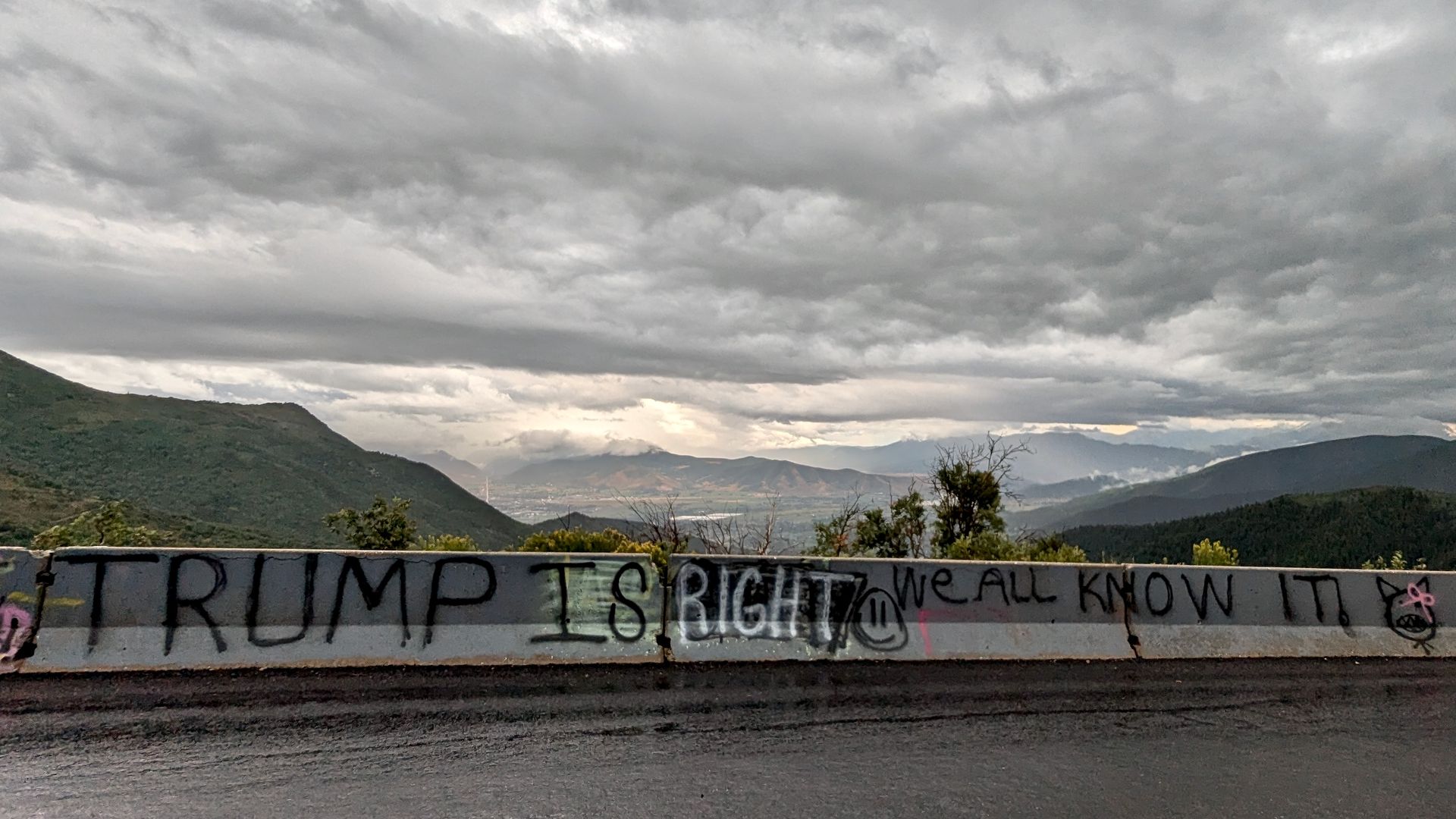 Graffiti on concrete guardrails on a mountain overlook states: "Trump is right" and "We all know it!"