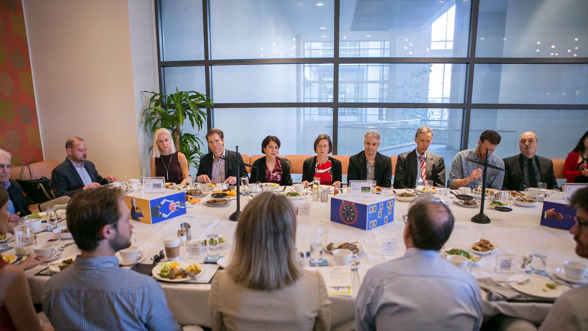 25 expert sitting at a round table ahead of breakfast discussion. 