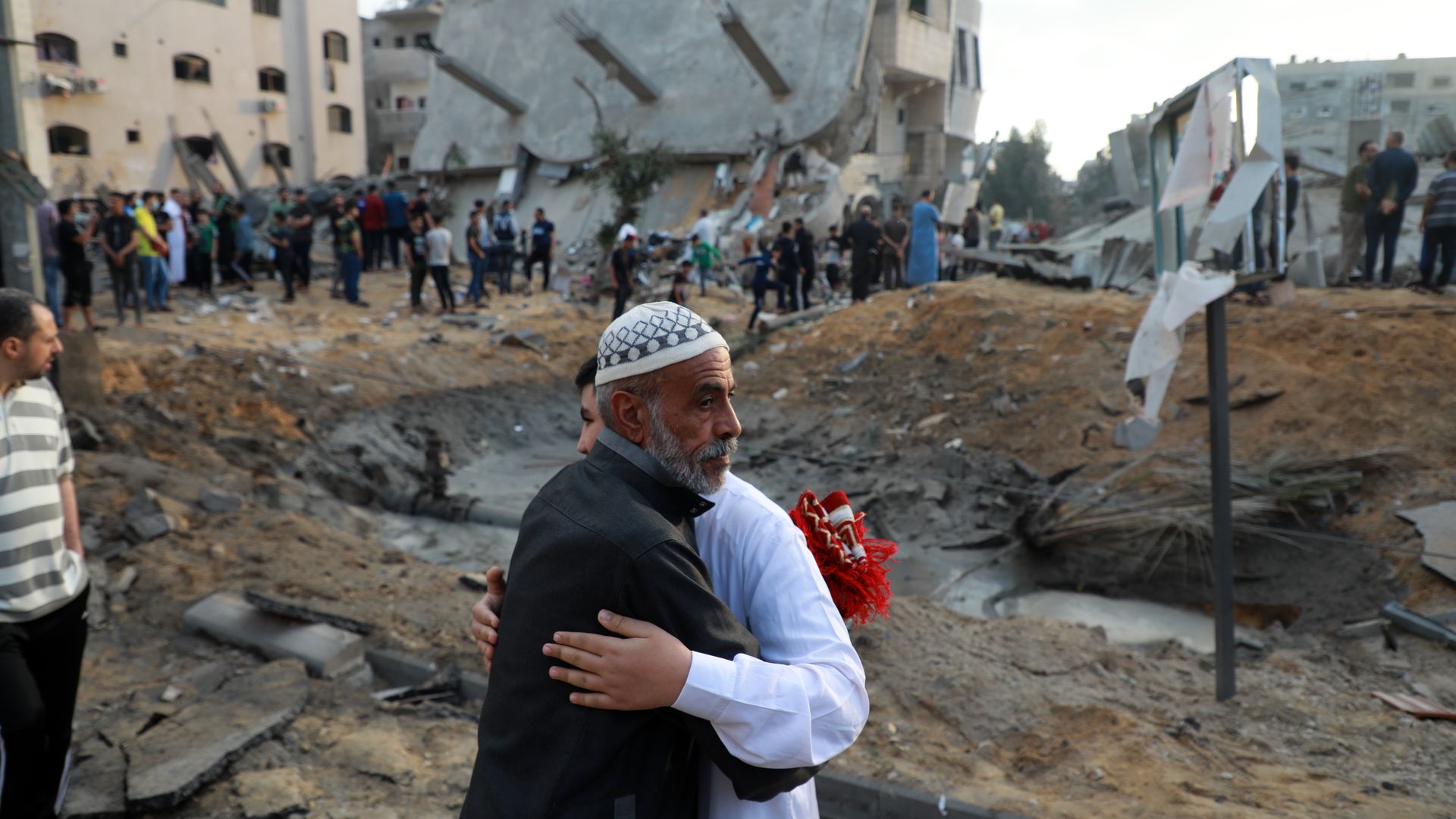 Palestinian Muslim men exchange Eid al-Fitr holiday wishes in front of a destroyed building in the northern Gaza Strip town of Beit Lahia, on May 13