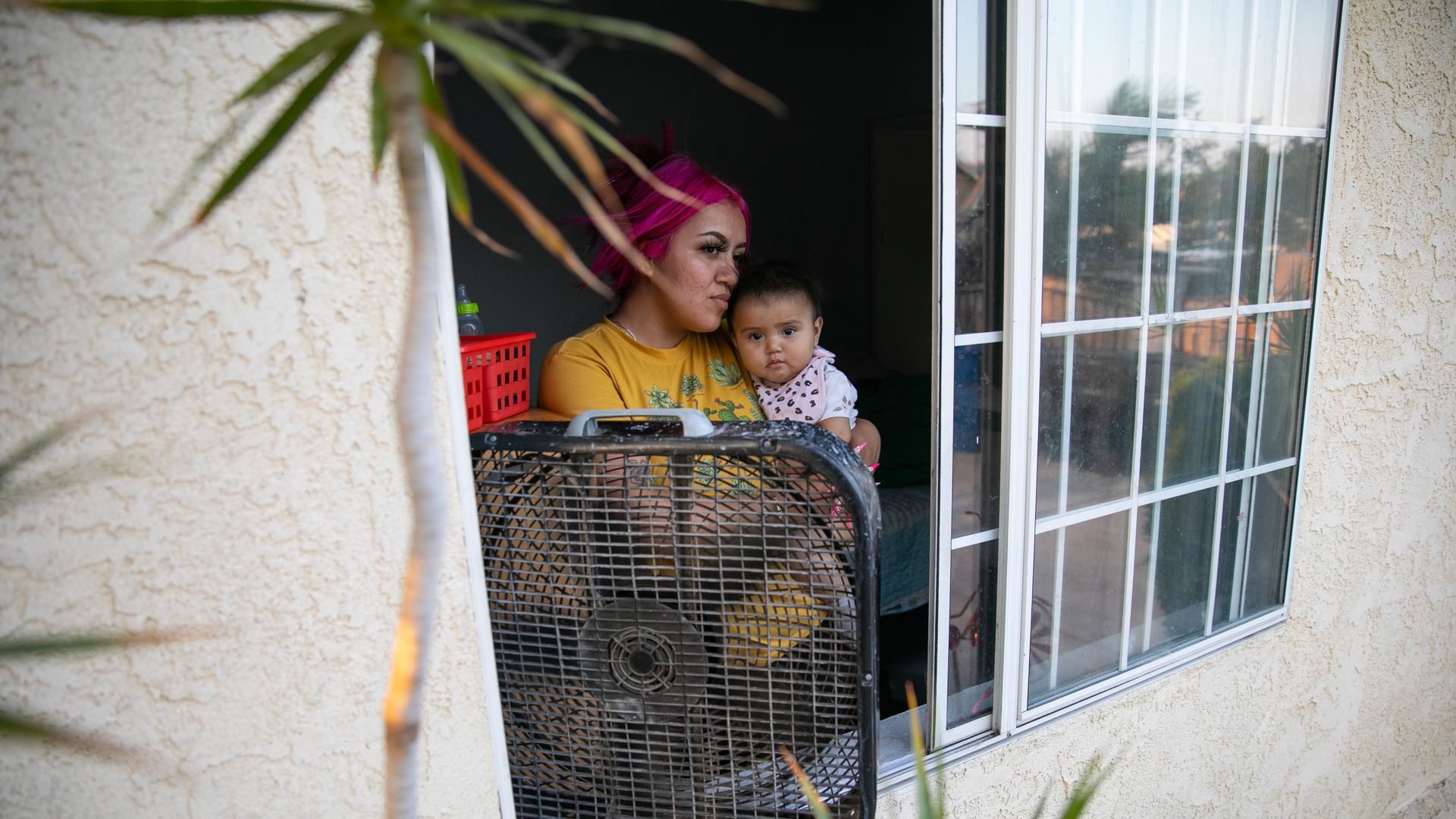 Mother cools her daughter by a fan