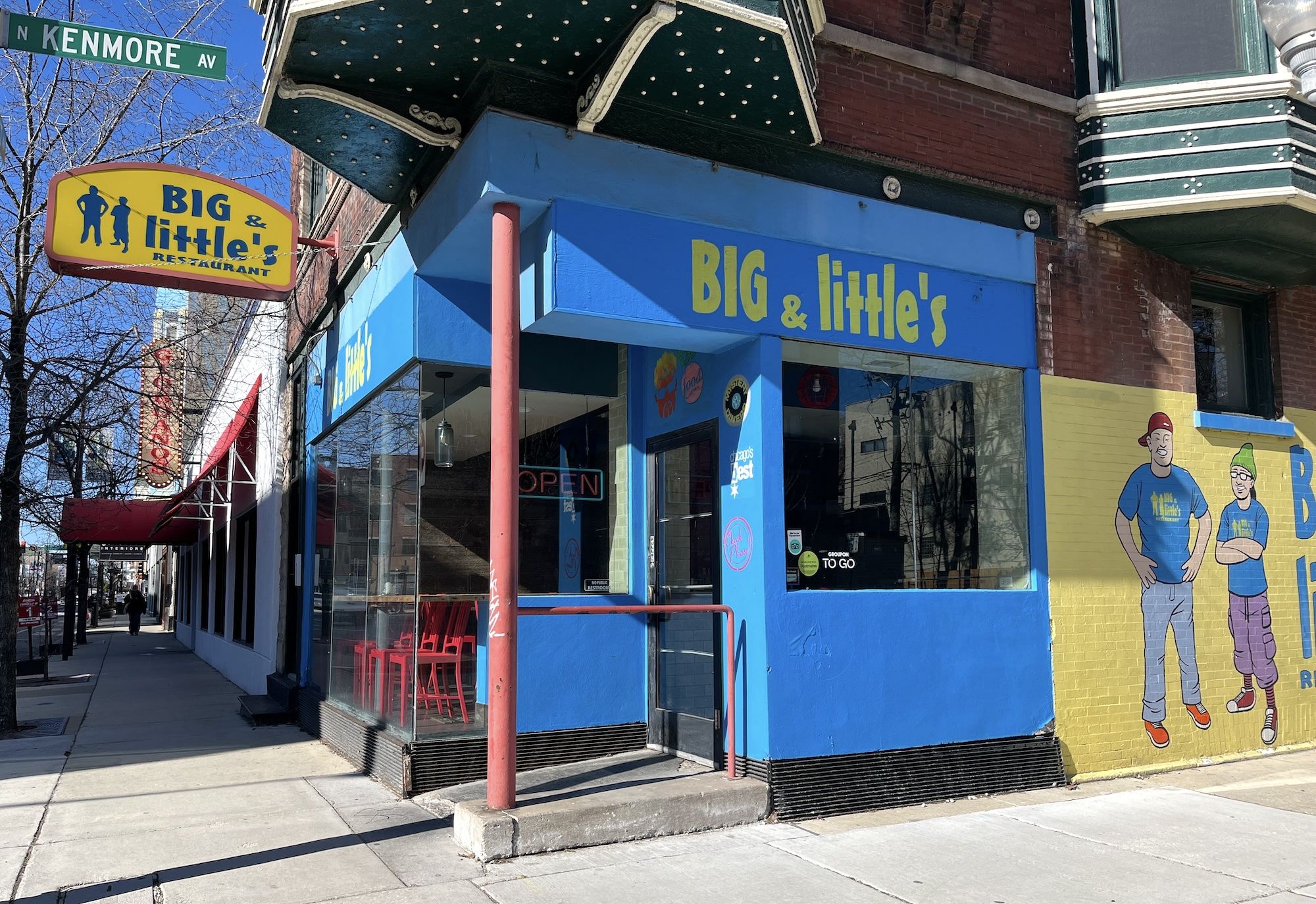 Yellow and blue painted exterior of restaurant with a mural of a larger and smaller man painted on it.