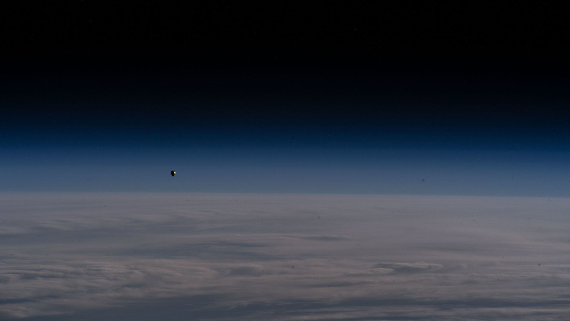 A Dragon spacecraft above the limb of the Earth against a black sky on the way to the ISS