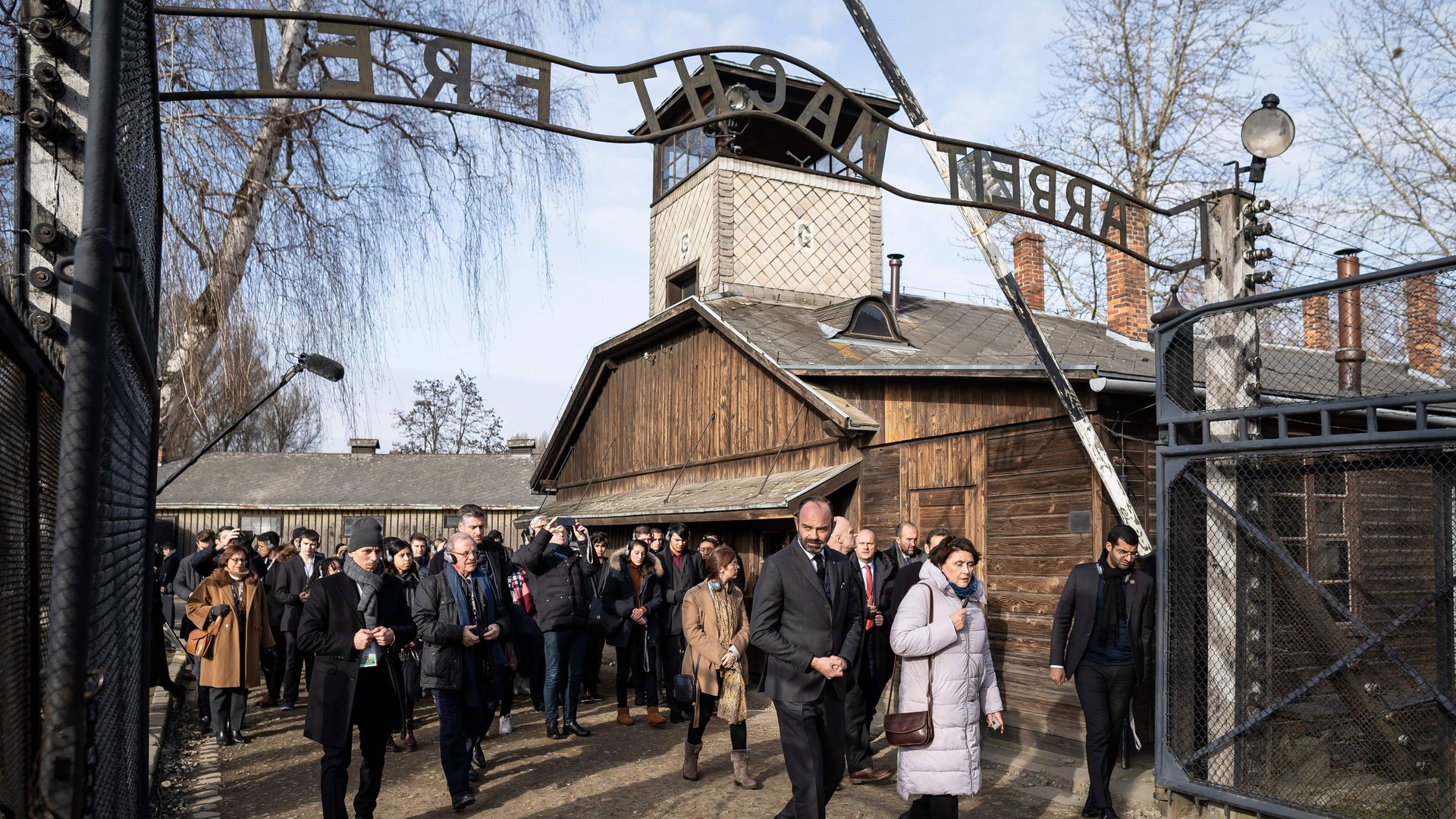 French Prime Minister Edouard Philippe walks through a gate with the inscription "Work sets you free" (Arbeit macht frei)