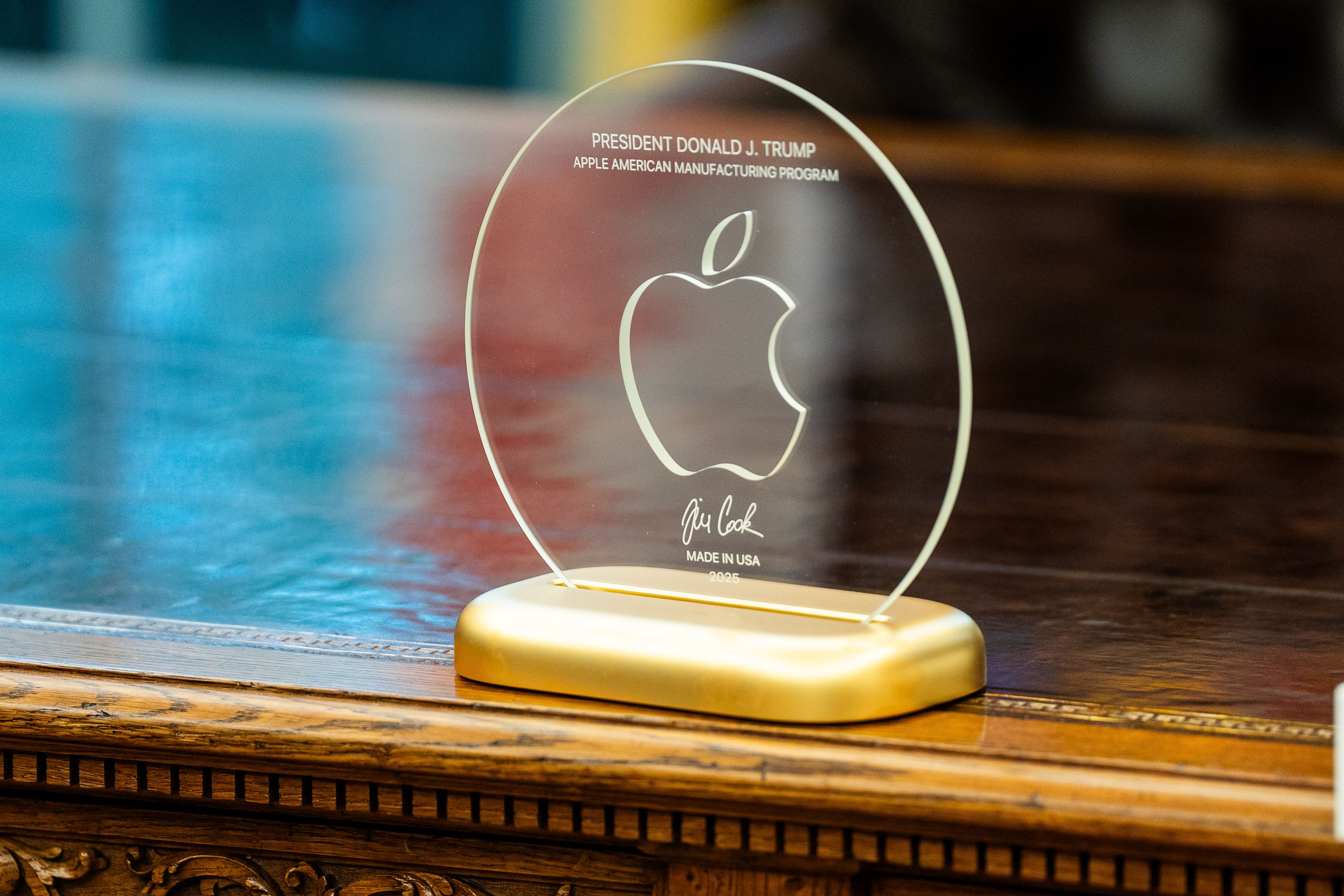 一塊印有蘋果標誌的透明圓盤放置在金色底板上。