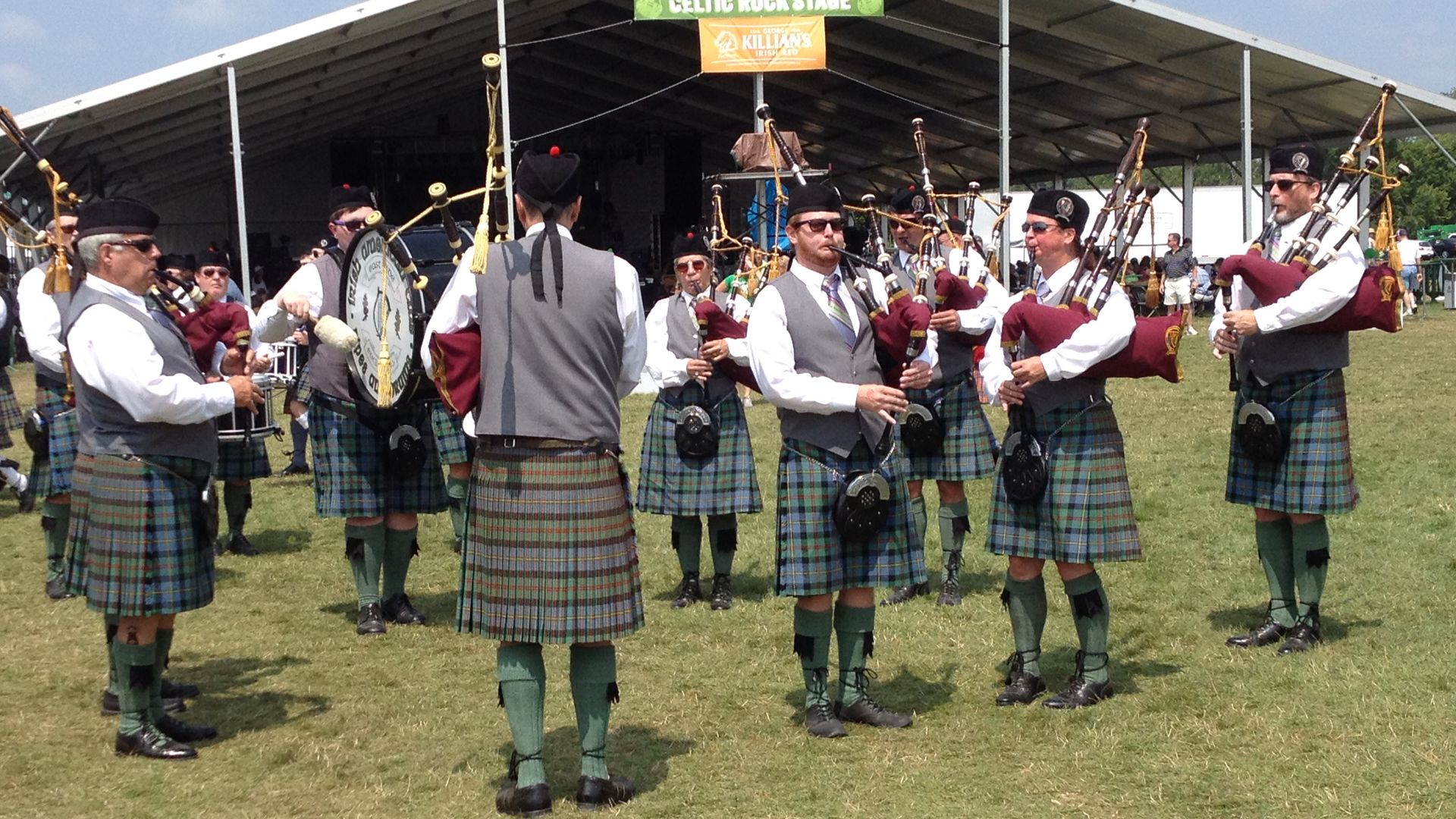 Men in kilts play the bagpipes outside a culture festival tent.