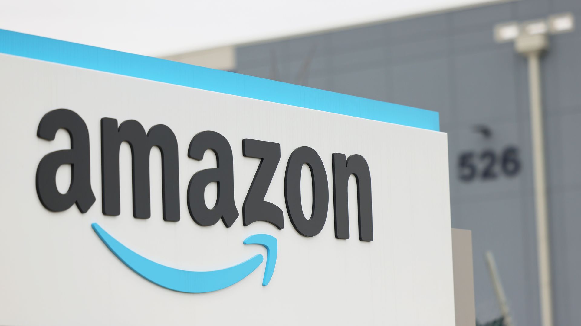Photo of a blue and white Amazon sign showing the company logo at the entrance to a warehouse facility
