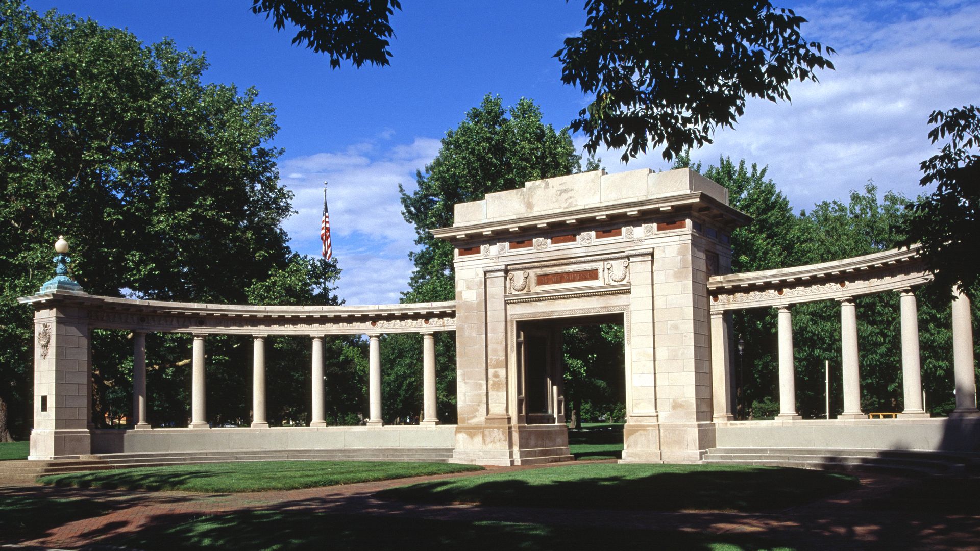 An arch and columns on a green field