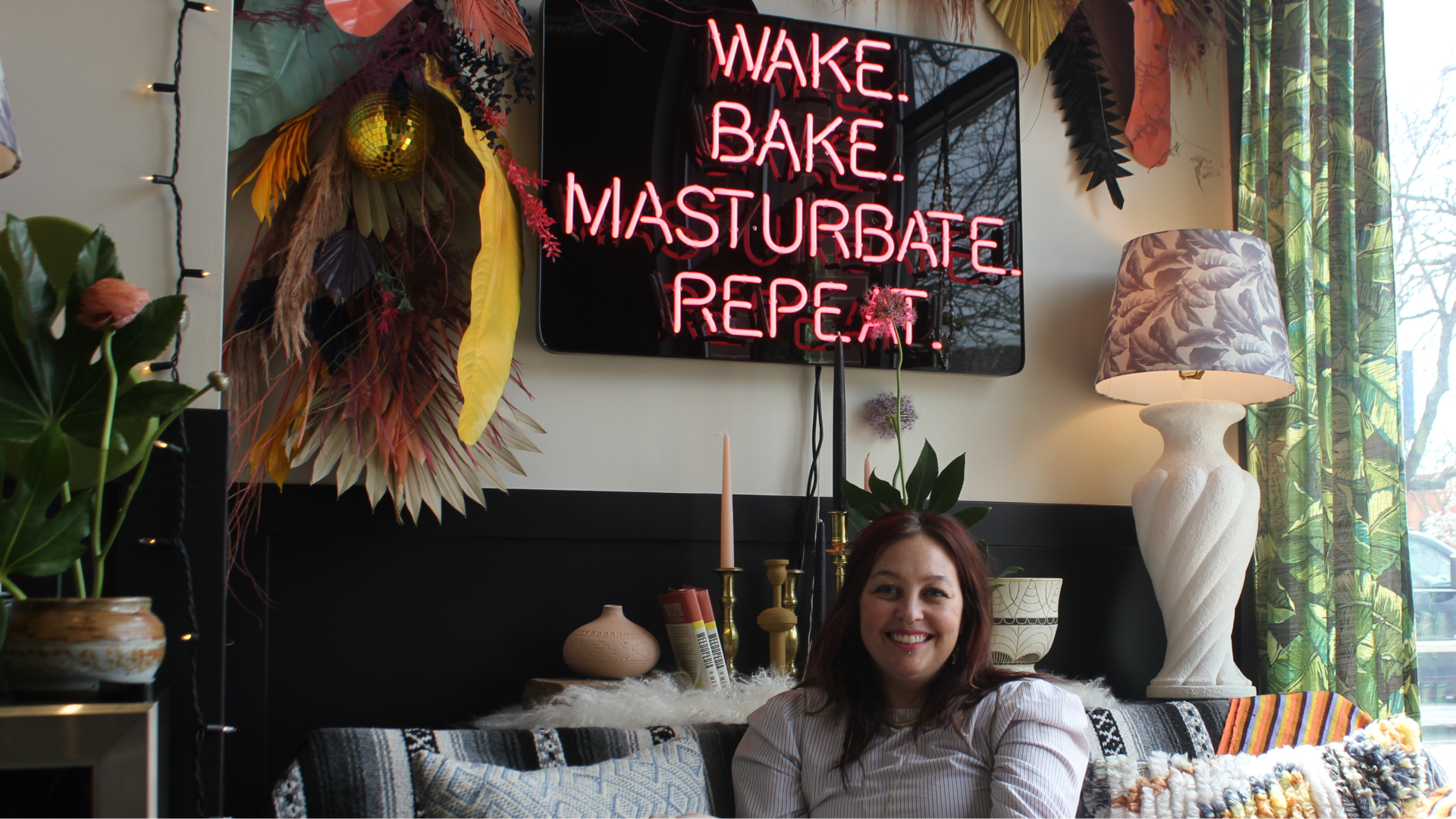 Andi in front of a "wake bake, masturbate, repeat" sign
