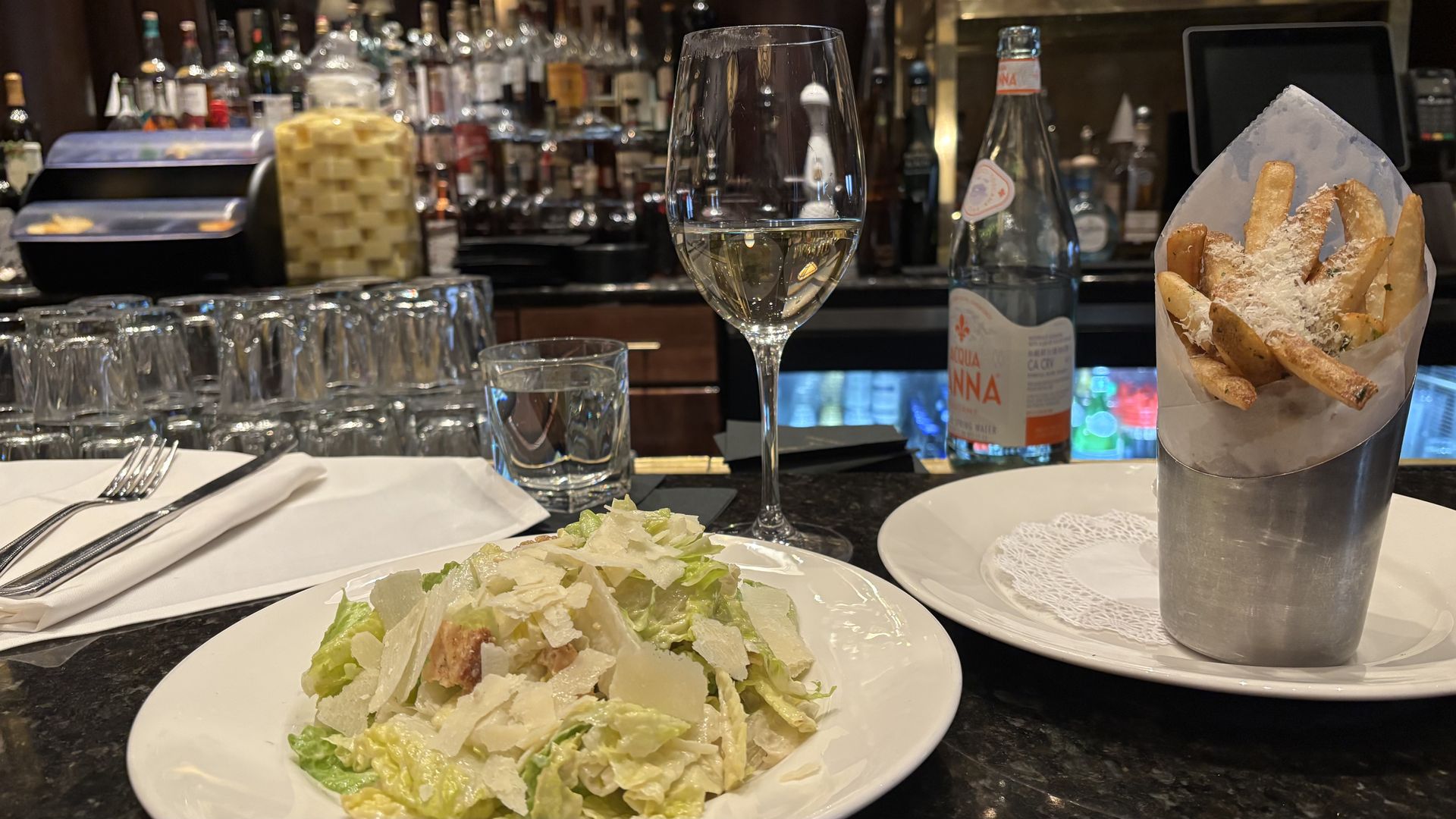 A caesar salad and fries on a bar