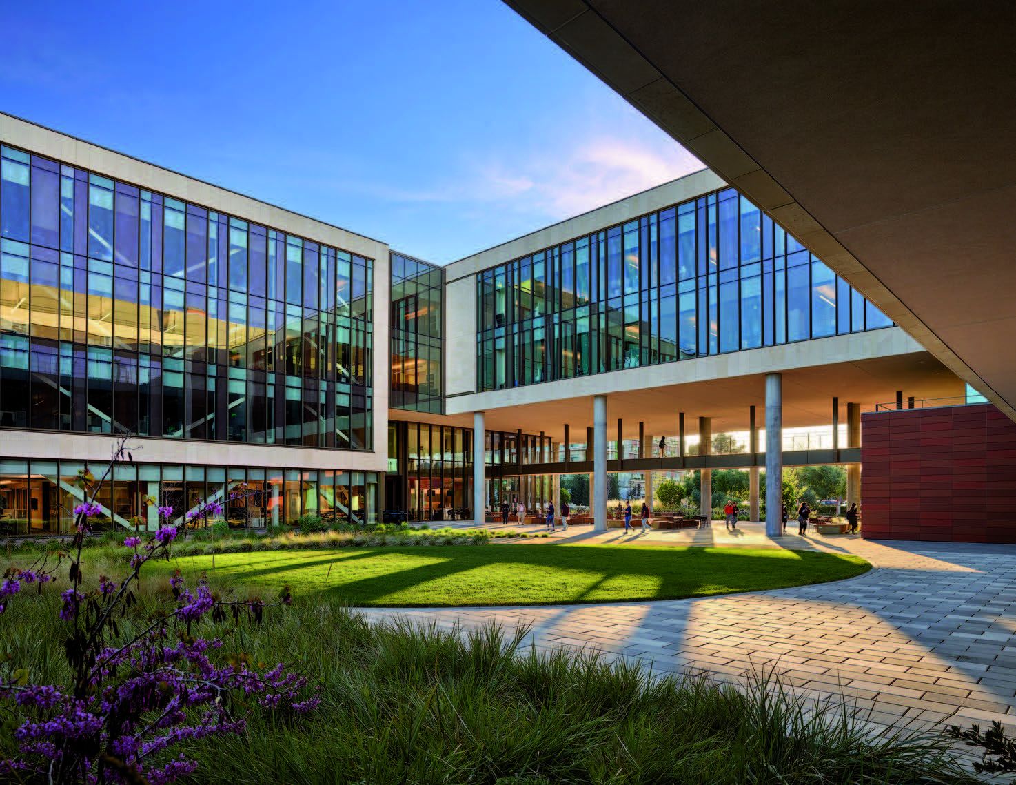 Photo of a glass building overlooking a lawn and flowers