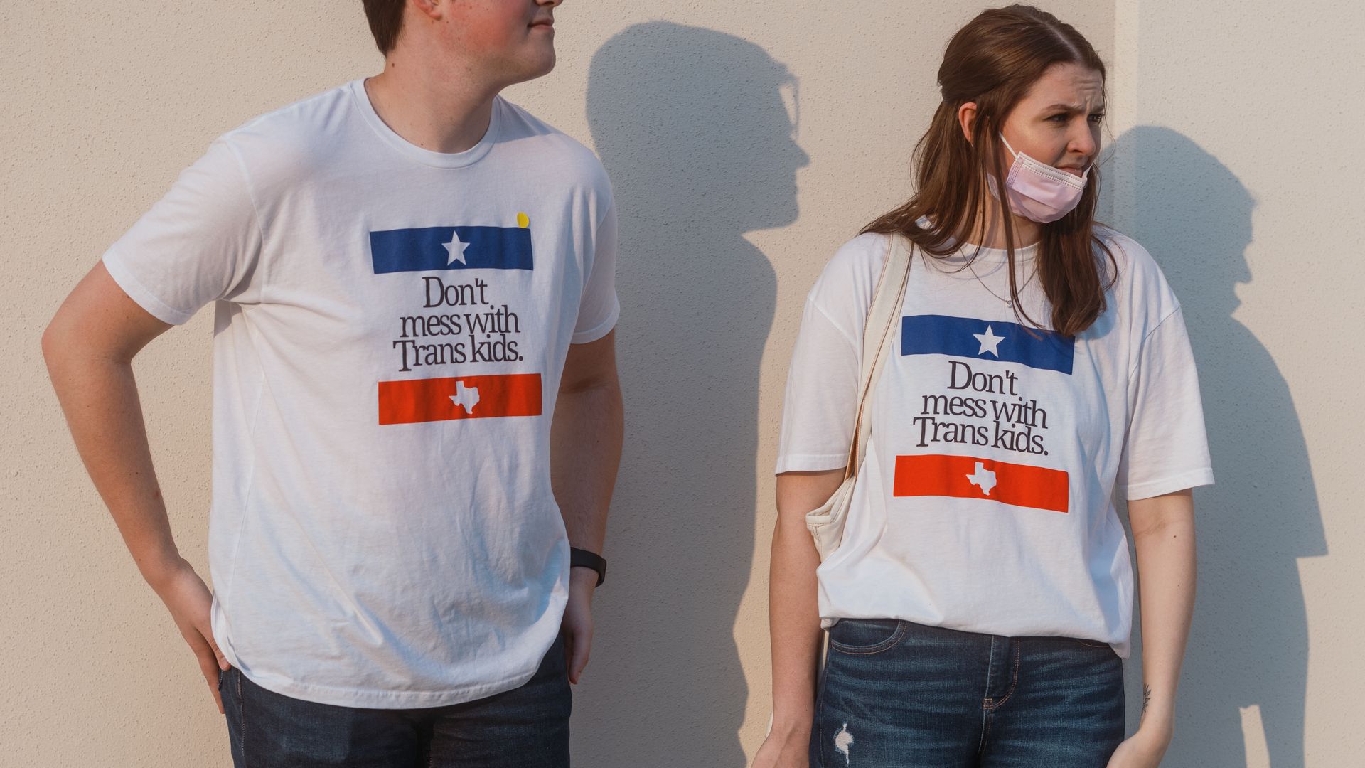 Picture of two people wearing shirts that say "don't mess with texas trans kids"