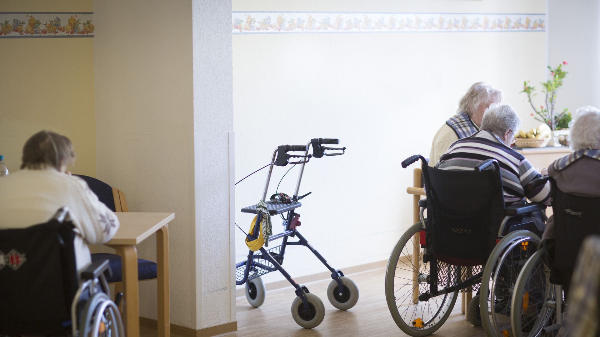 Elderly sit around tables in their wheelchairs.