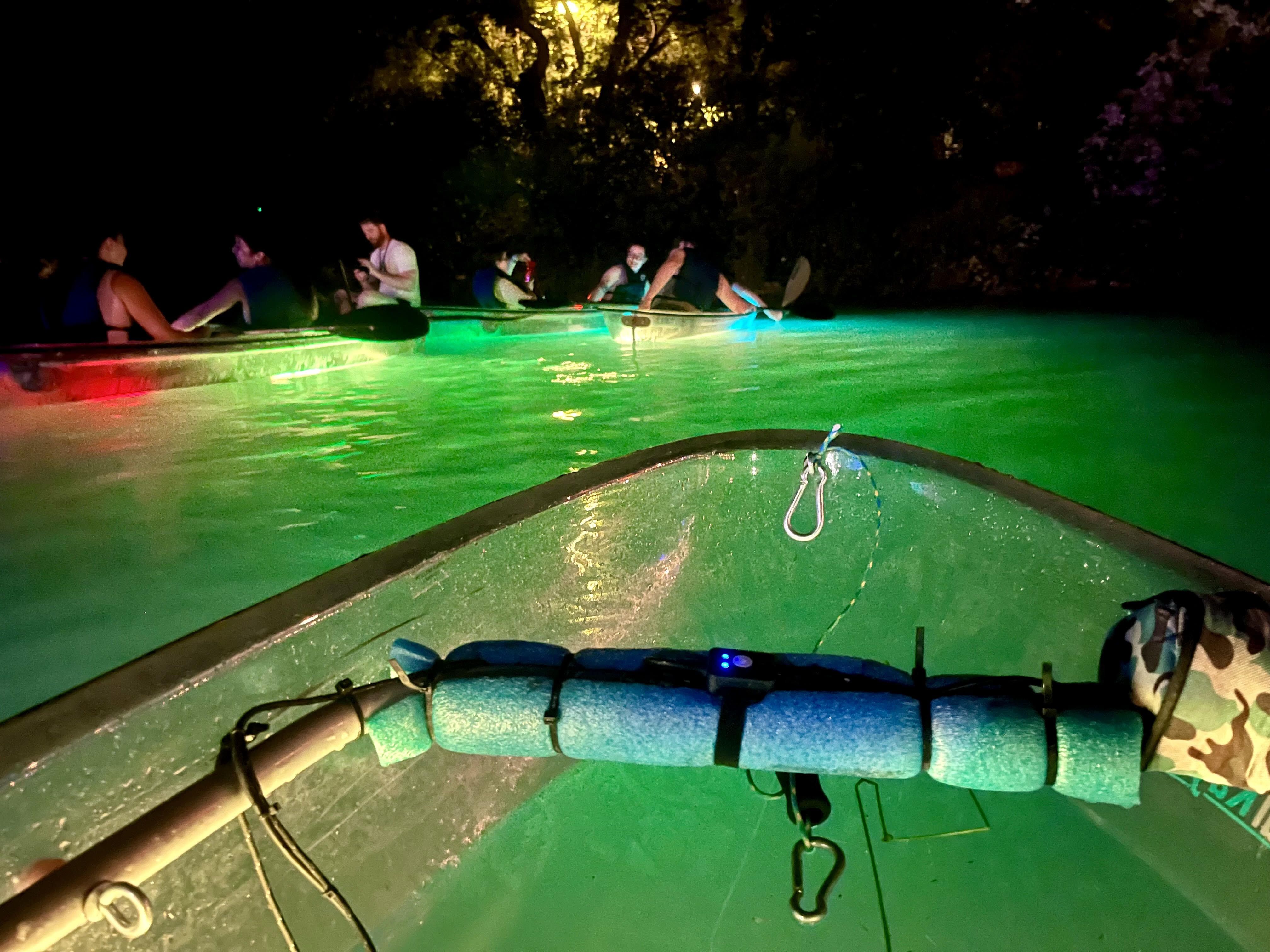 A glass bottom kayak floats on a river at night. 