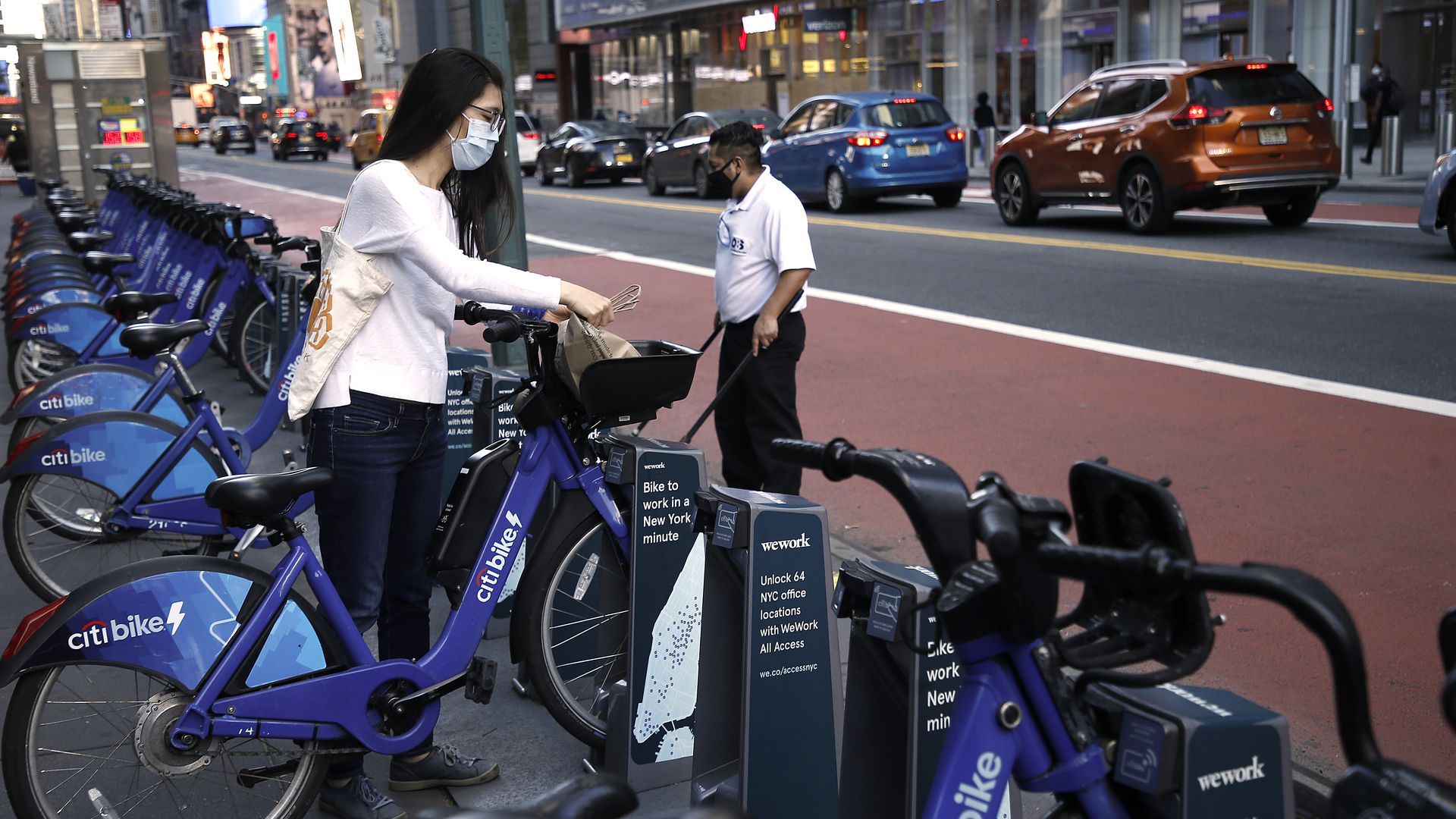 A woman rents a bike at a streetside Citibike parking location.