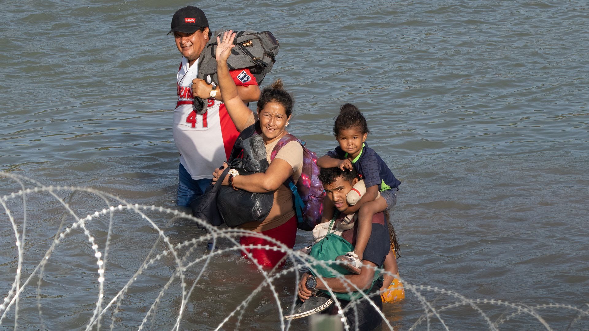 A family in the Rio Grande near barbed wire. 