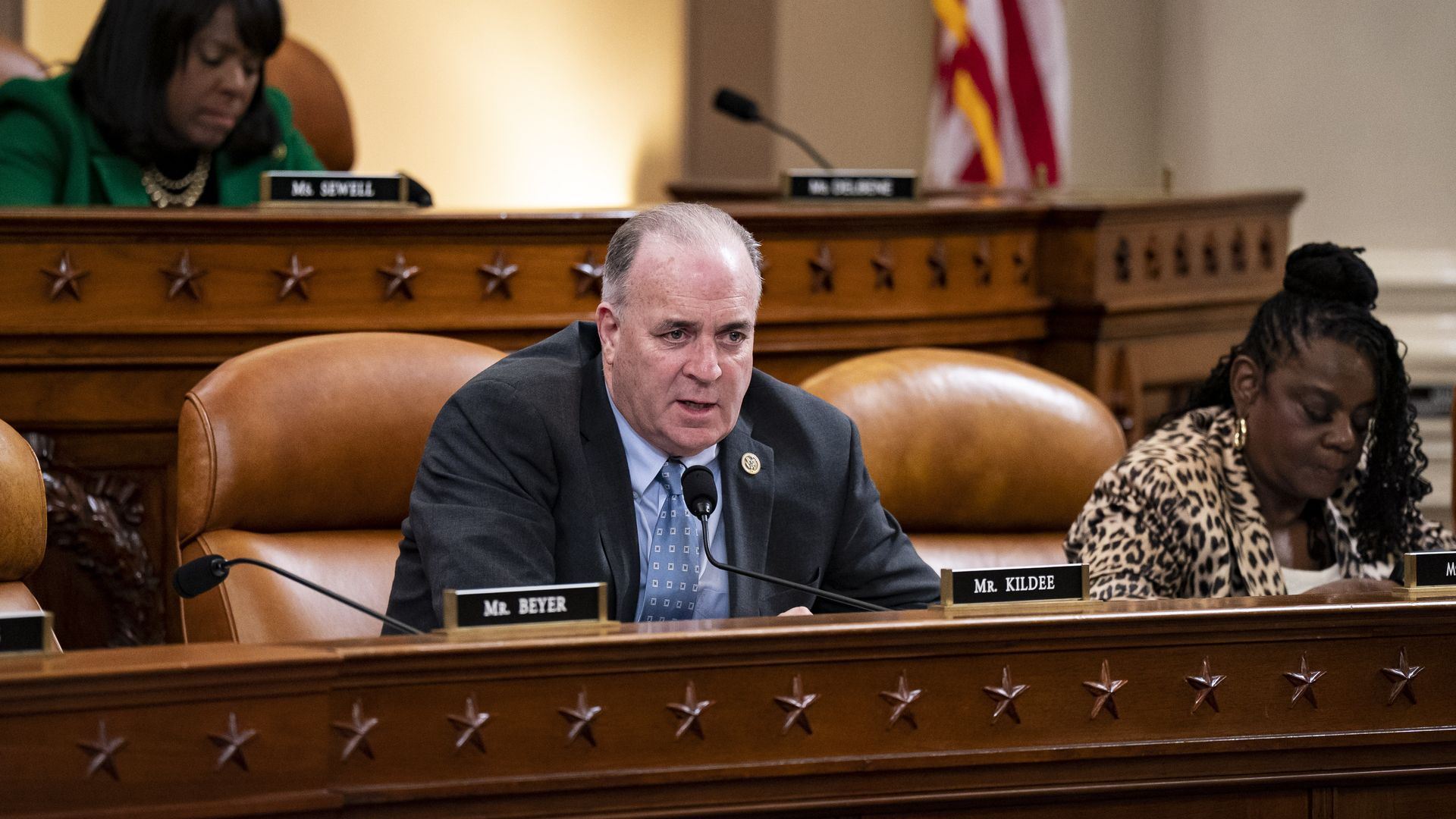 Rep. Dan Kildee, wearing a grey suit, blue shirt and blue tie, speaks into a microphone while sitting behind the dais at a committee hearing.