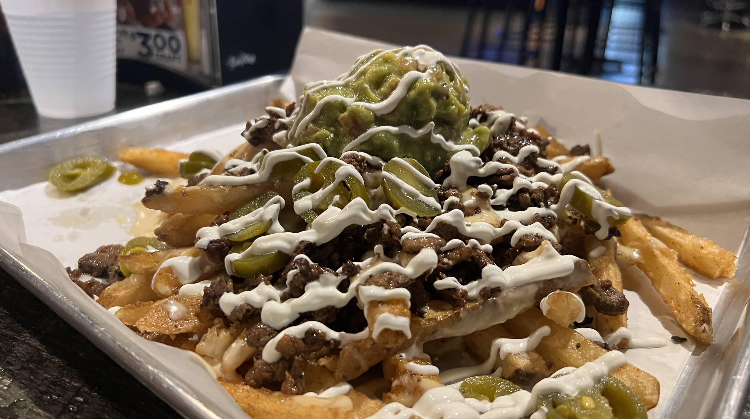 A heap of fries, sour creme, beef and cheese