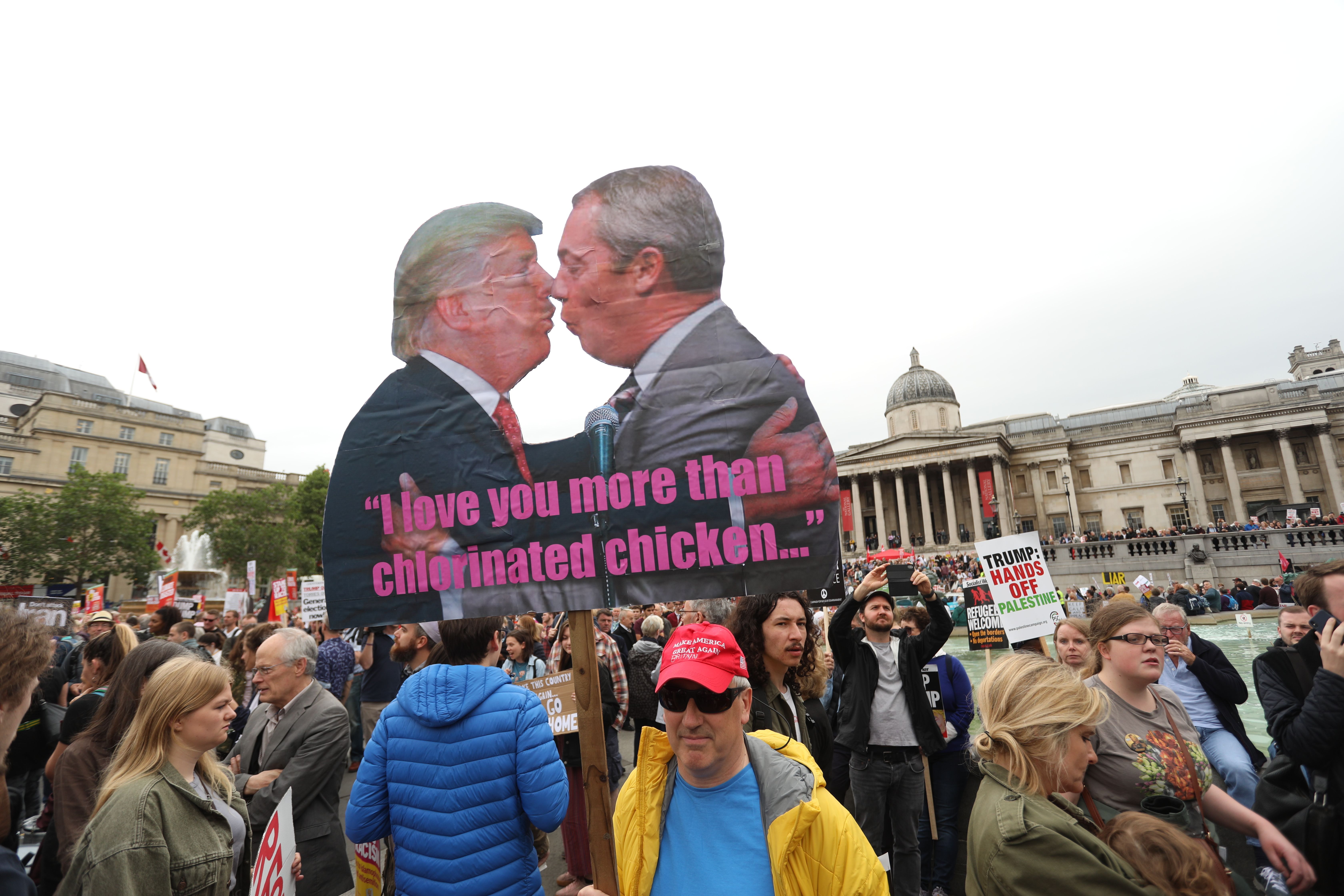 Anti-Trump protesters hold a placard depicting US President Donald Trump (L) and Brexit Party leader Nigel Farage (R) during a demonstration.