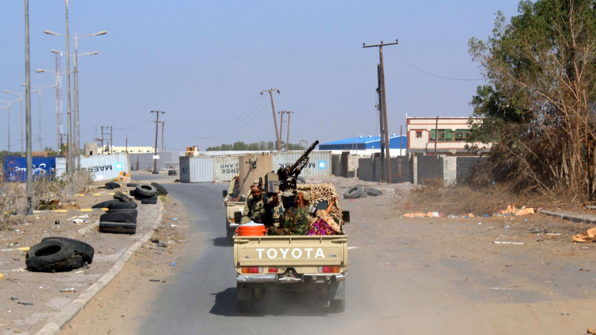 Yemeni government fighters in a truck on an empty, dusty road