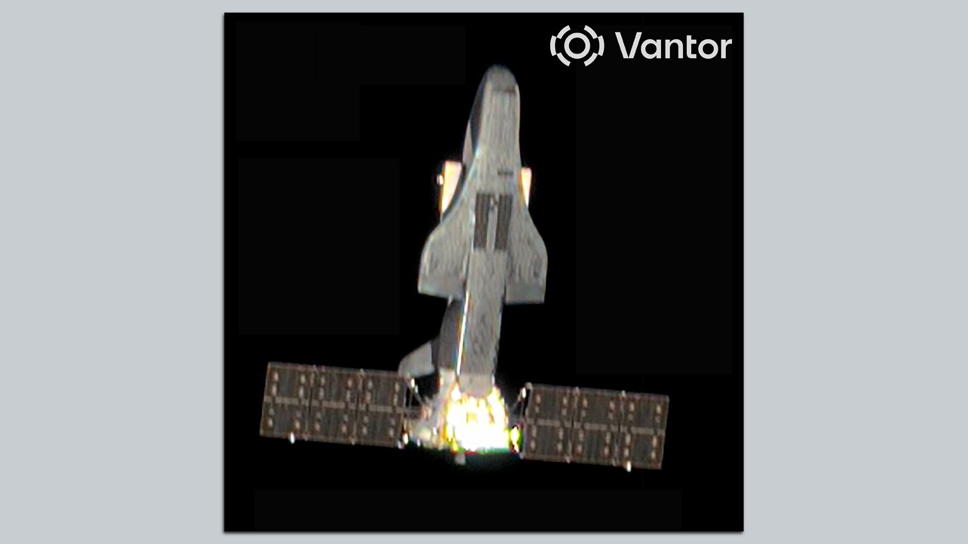 Gray space shuttle-like spacecraft upright with engines firing at the base, a long solar-panel array below, against a black background, with a white Vantor logo in the upper right corner.