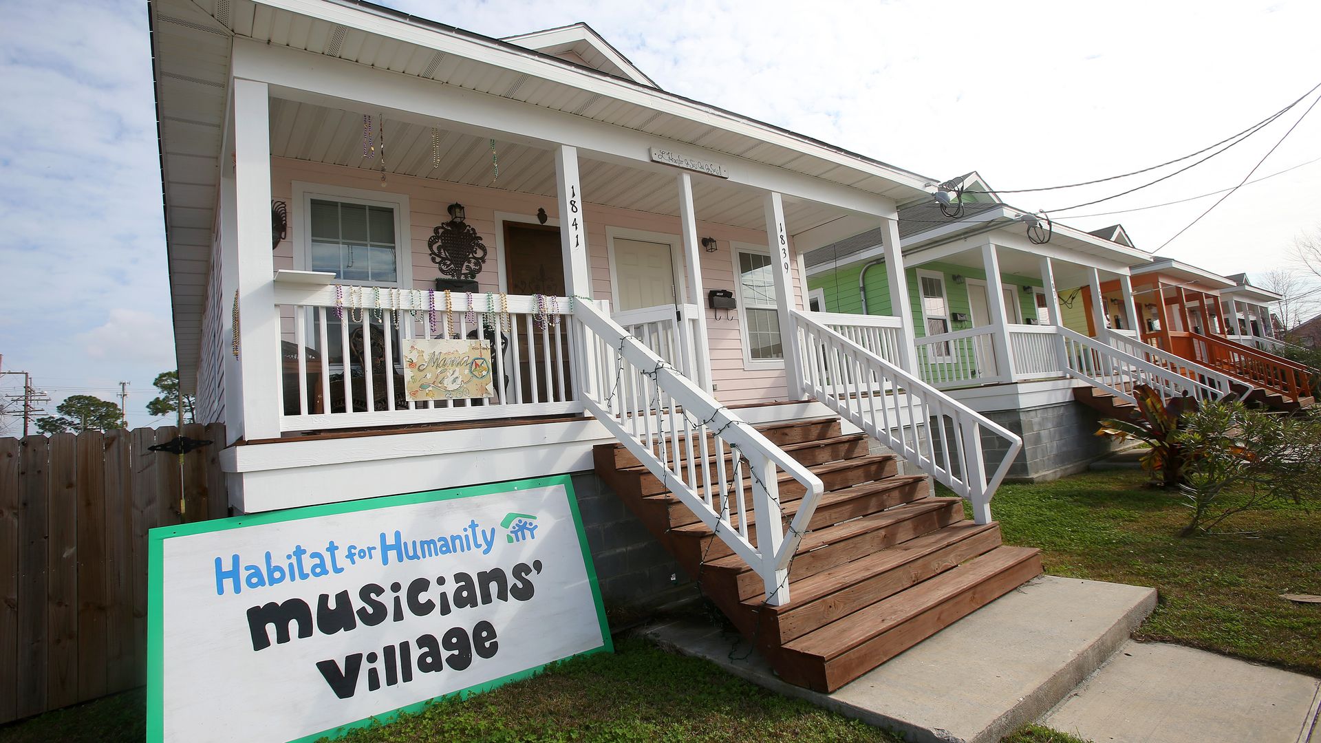A view of a row of colorful homes. A sign sits out front of one of the homes and says "Habitat for Humanity Musicians' Village."