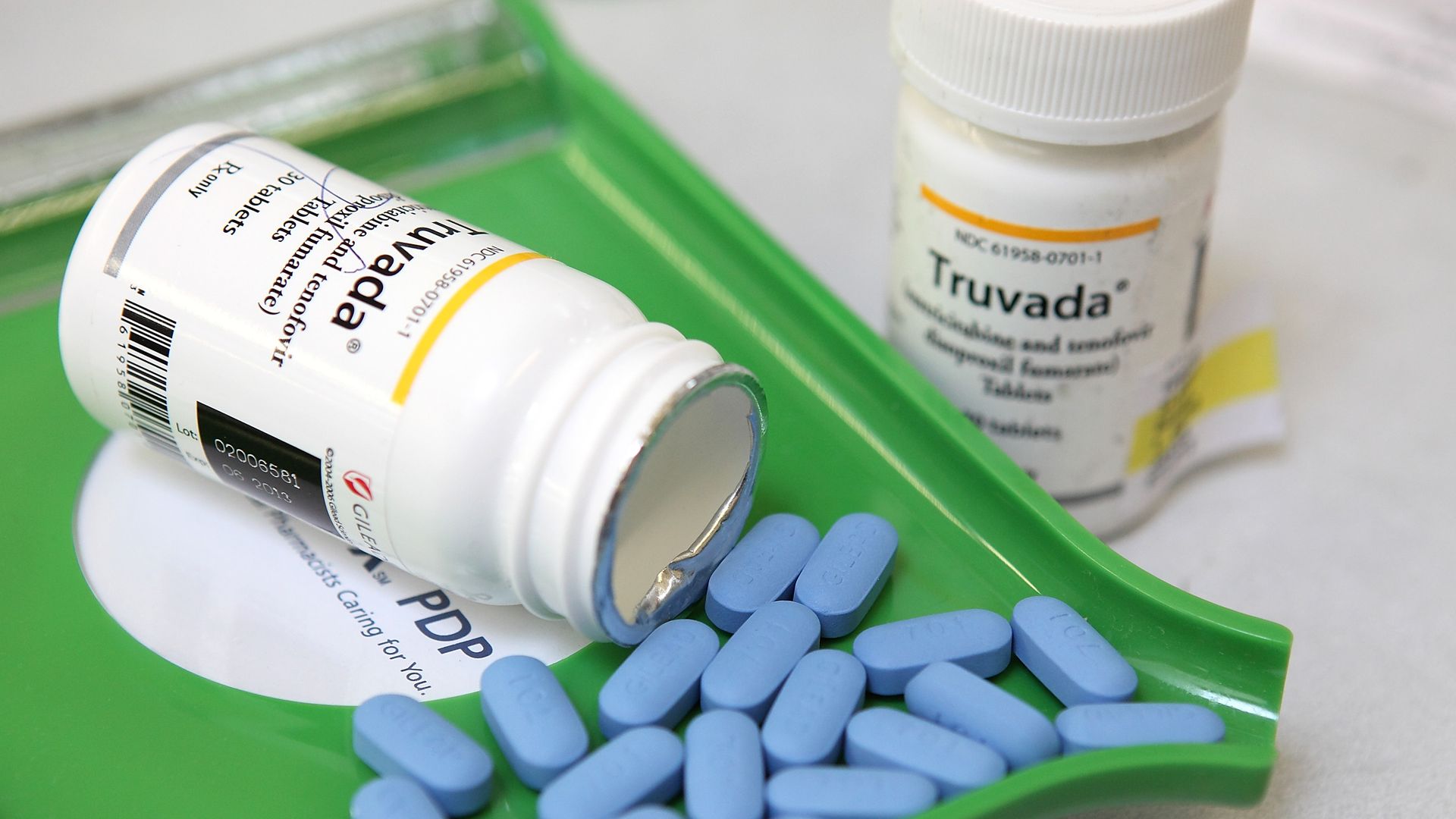 Two bottles of Truvada with the blue pills sitting in a green tray.