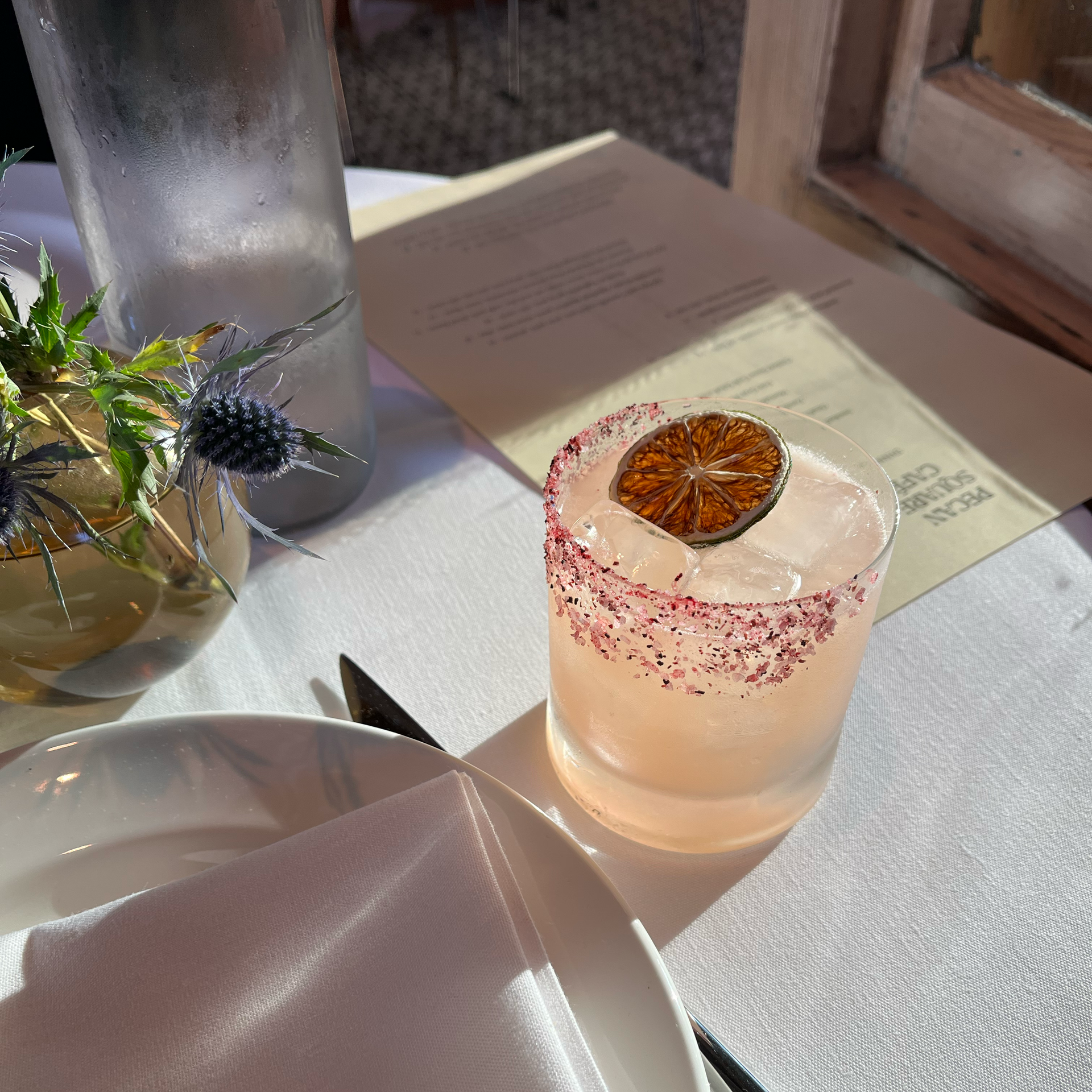A mezcal margarita sits in the sunlight on a table